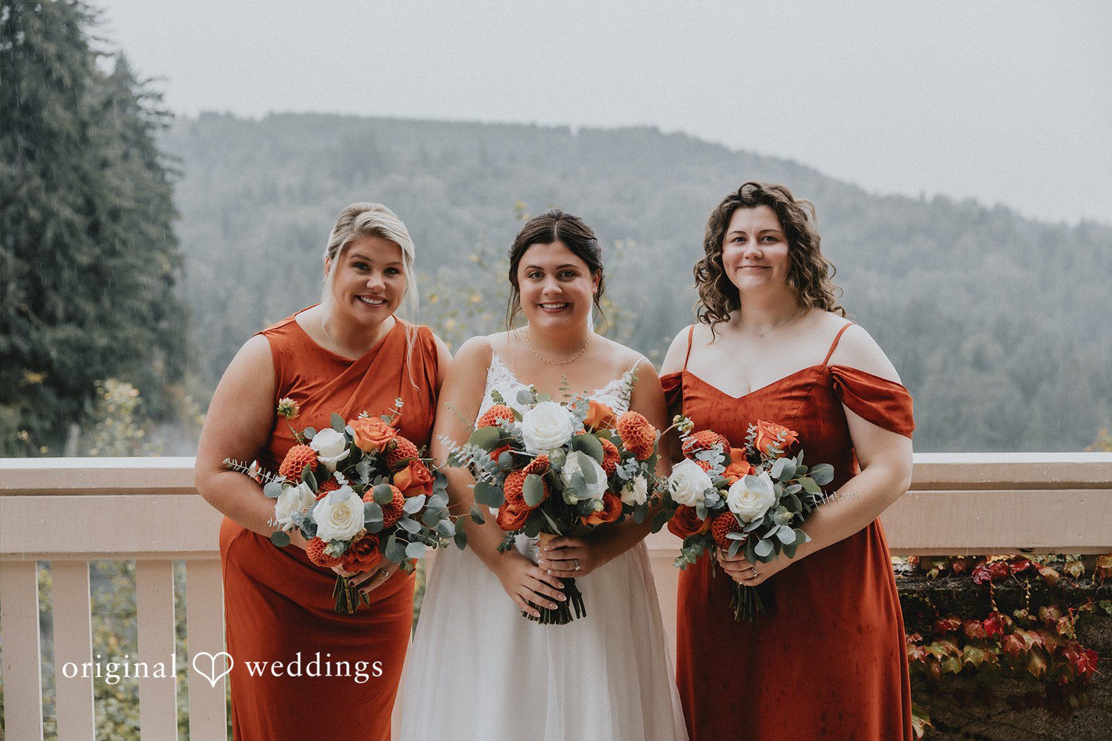 Bride and bridesmaids in matching rust-colored dresses standing together.