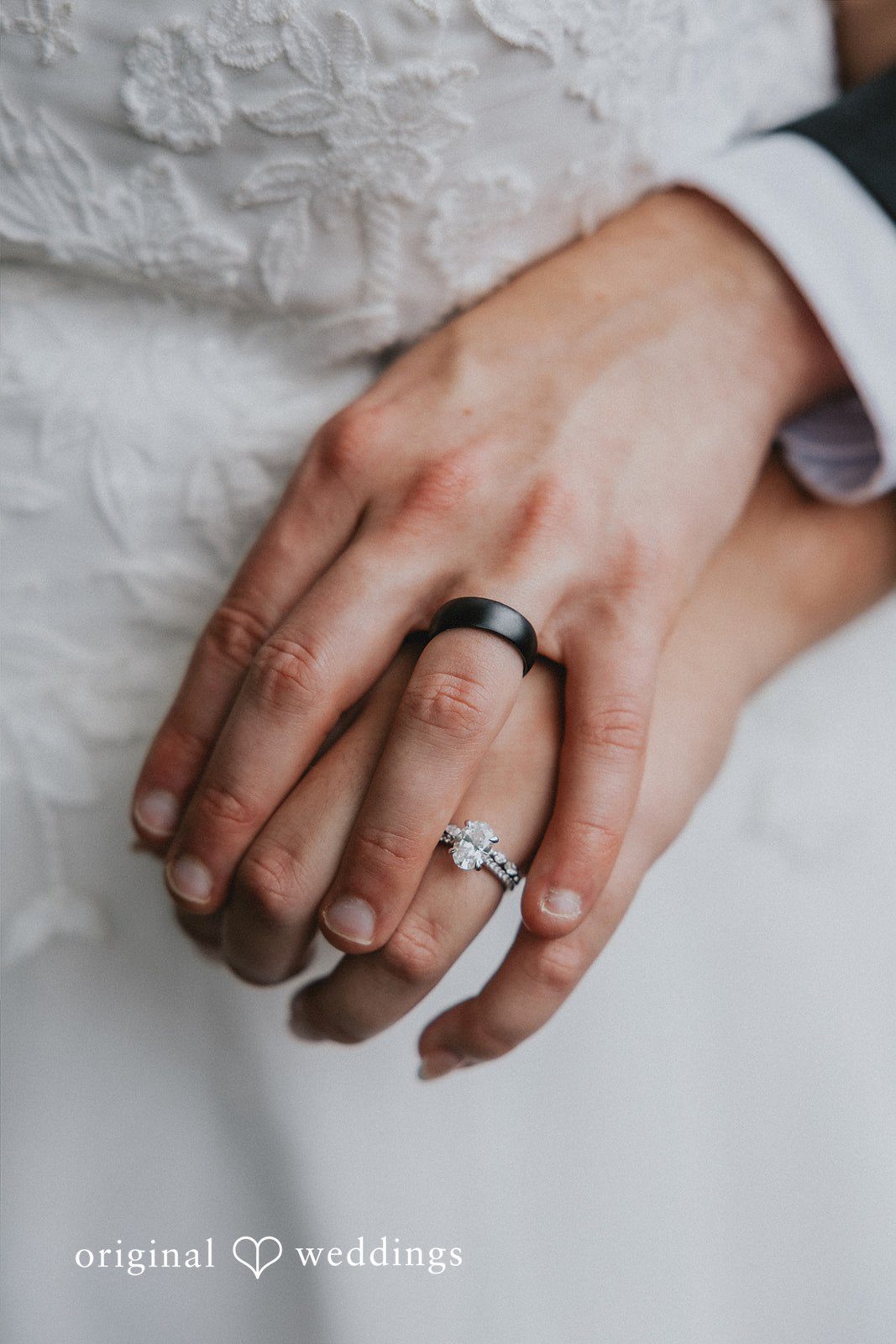 A close-up shot of two hands clasped together, showing a wedding rings.