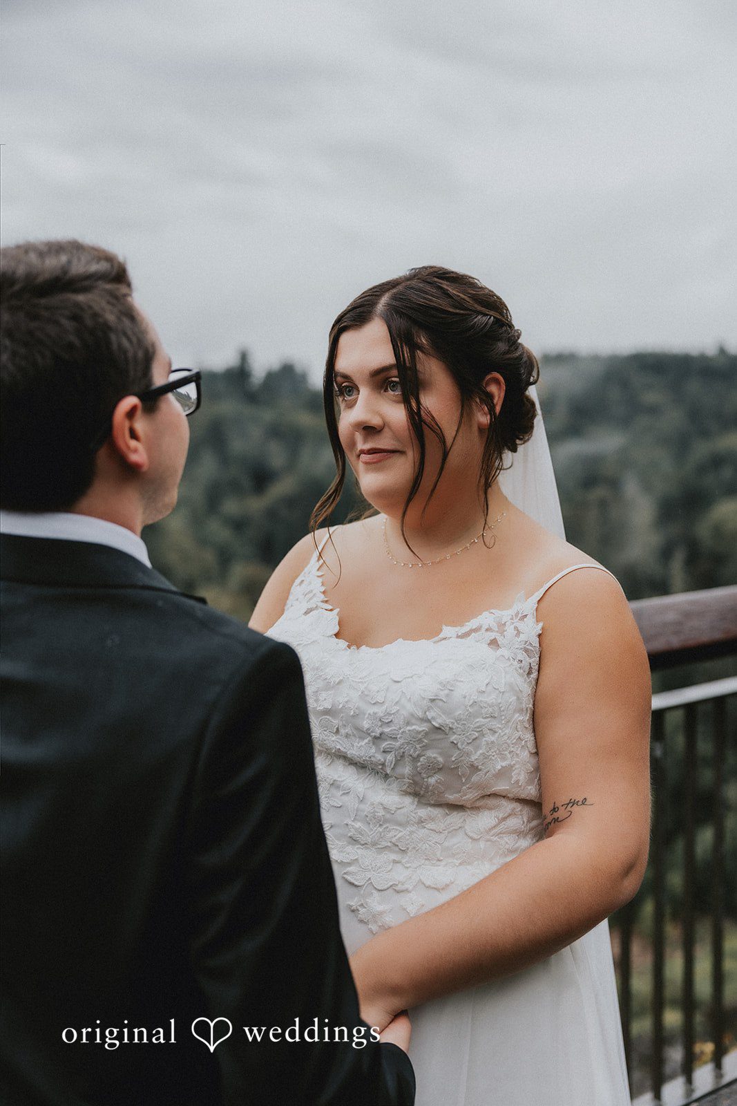 A bride and groom sharing a look while posing in front of a misty mountain view.