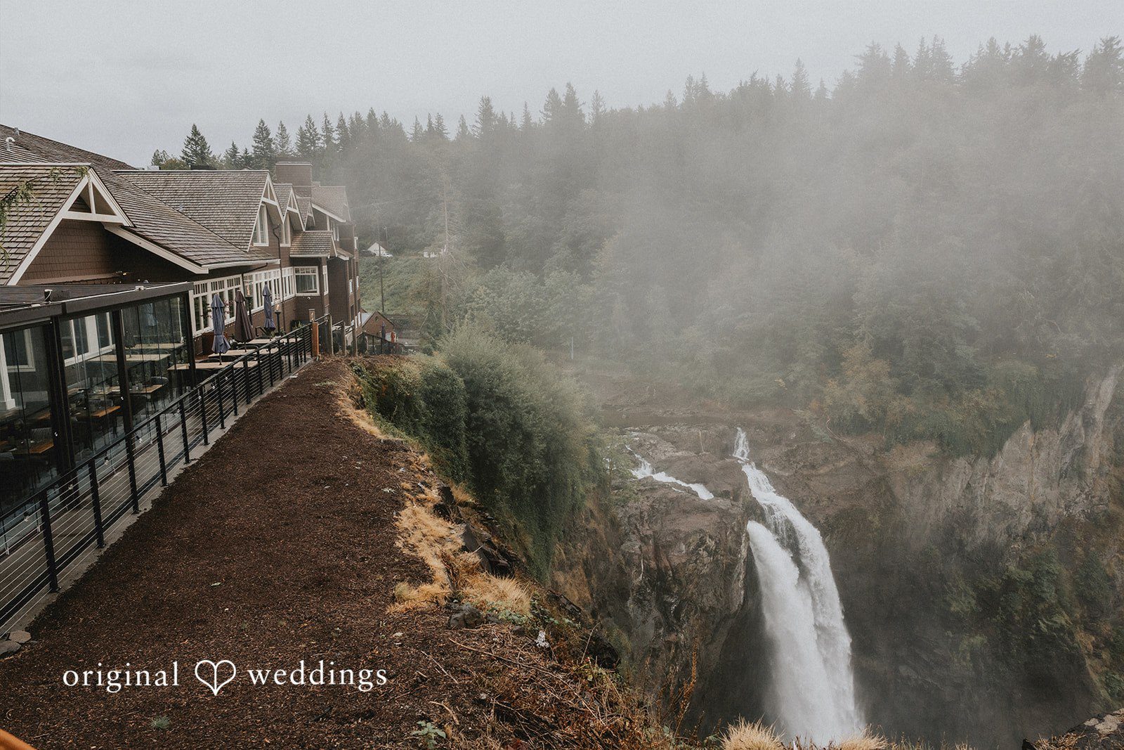 A building perched on a cliffside overlooking a waterfall.