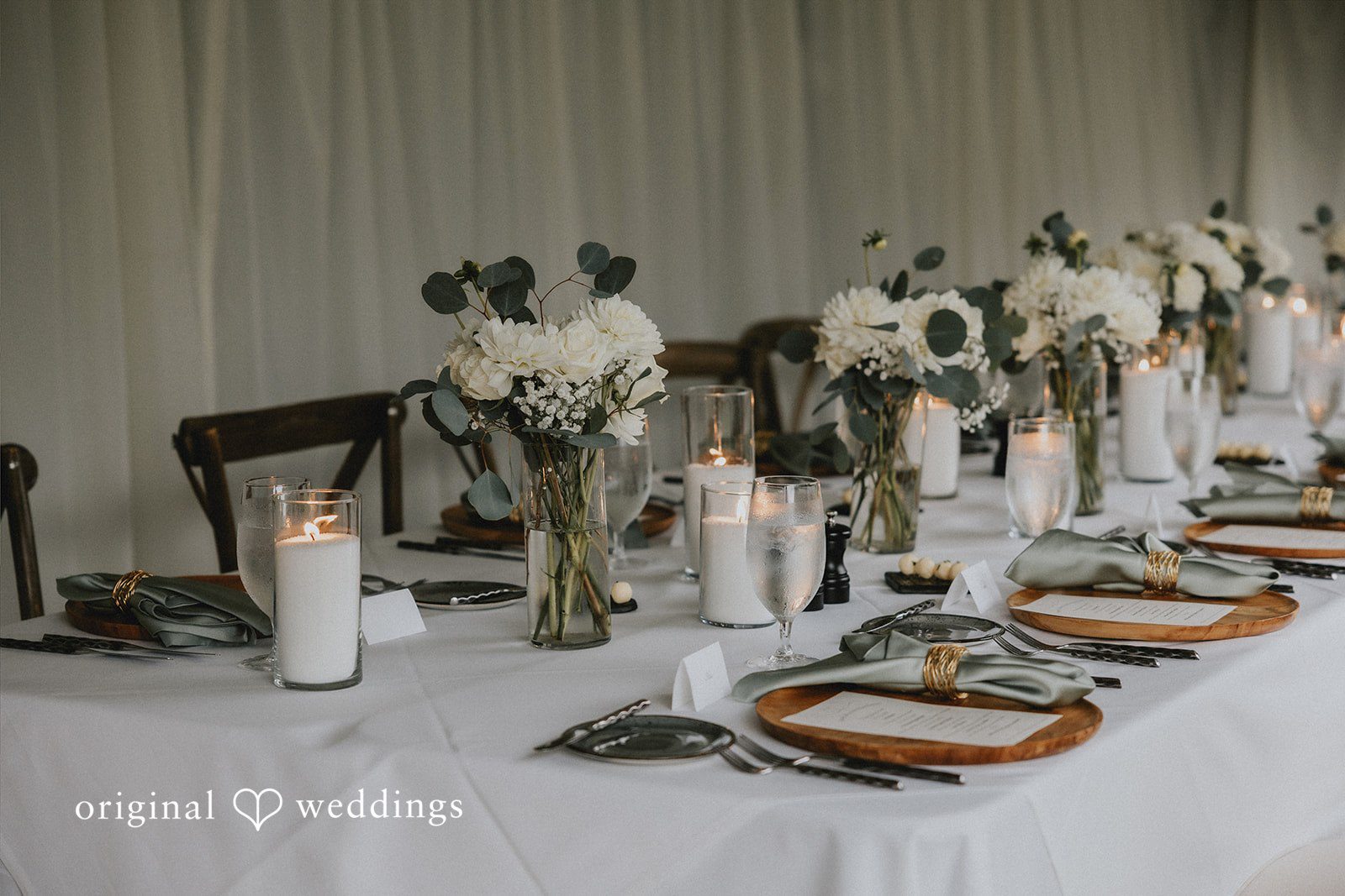 A close-up of a reception table setting decorated with tall candles.