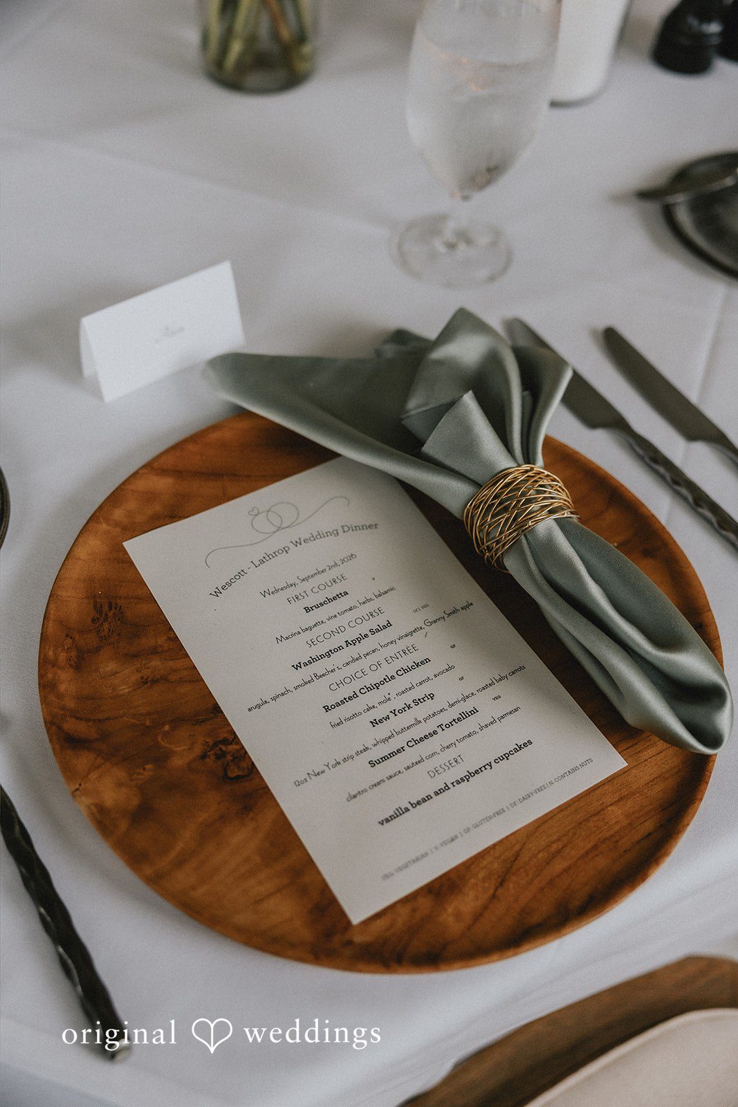 A wooden charger plate with a wedding menu card placed on top.