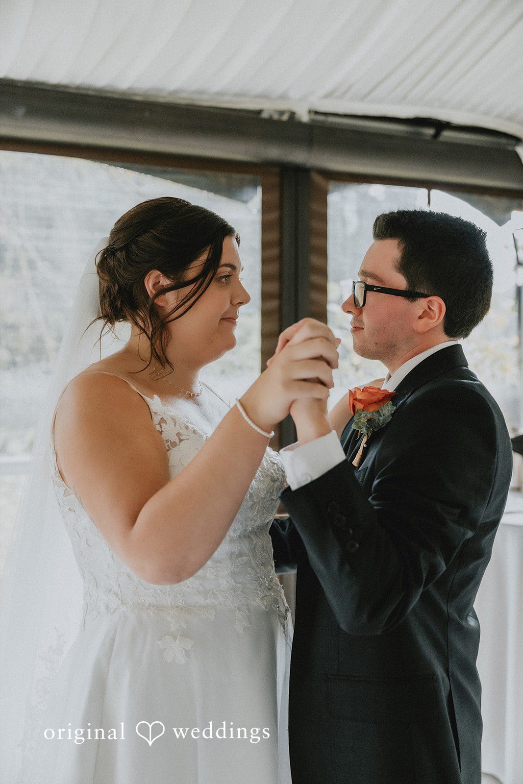 A bride and groom facing each other while dancing at their wedding reception.