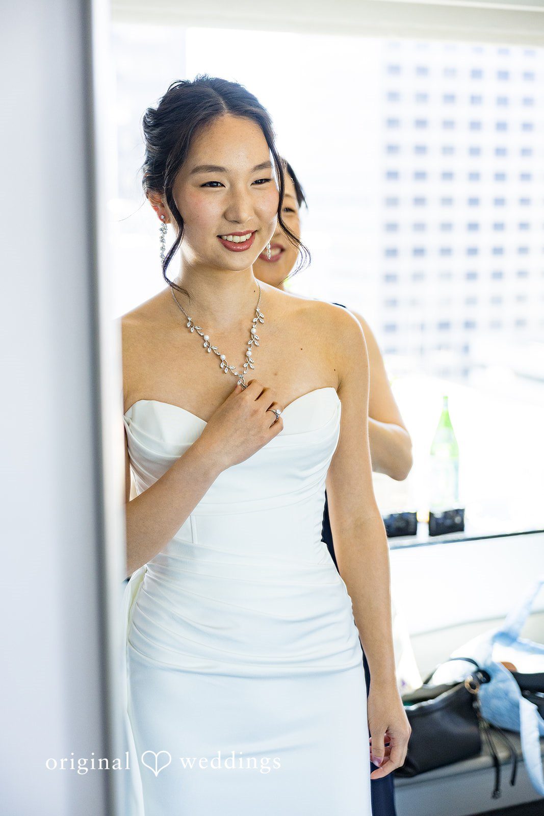 Emily + Paul A smiling bride in a strapless white wedding gown posing gracefully for a portrait.