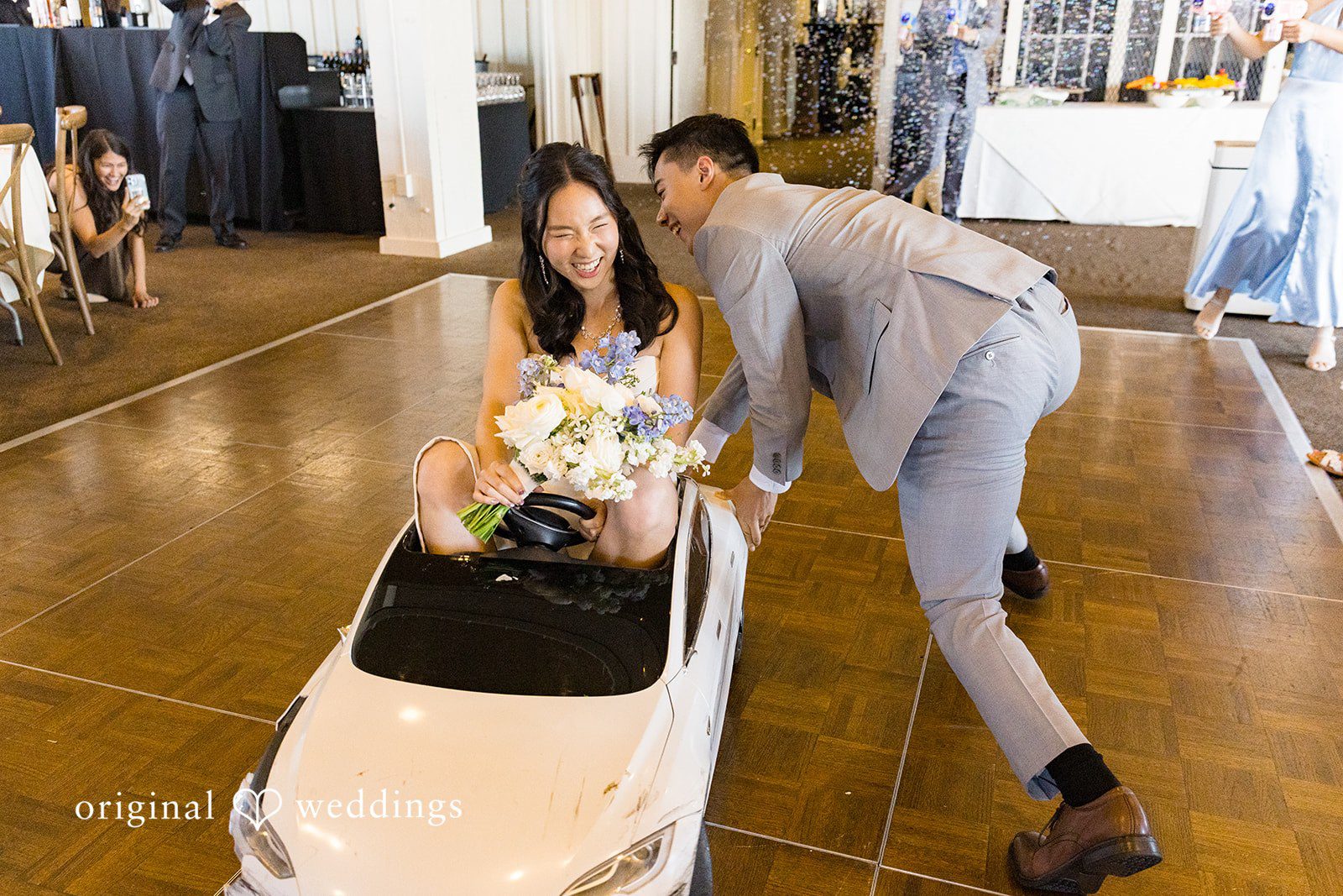Emily + Paul A groom guiding his bride as she sits inside a white toy convertible car on the dance floor.