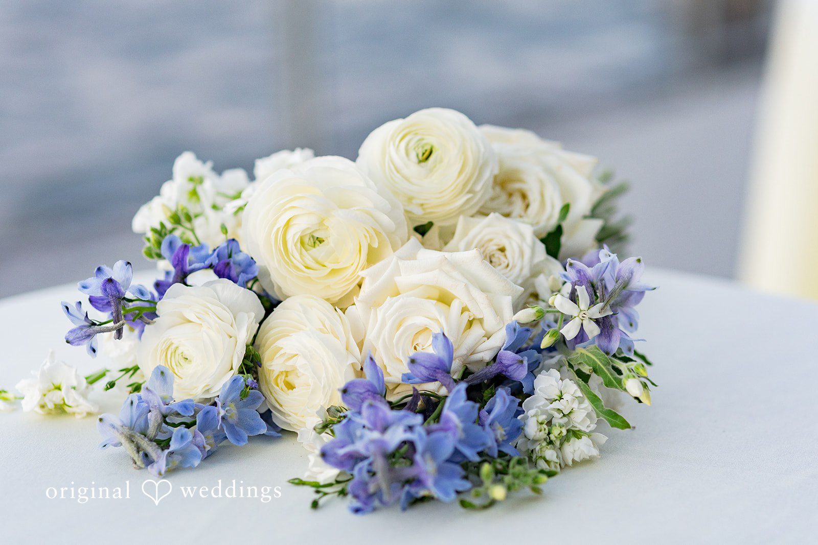 Emily + Paul A beautiful wedding bouquet composed of white roses and clusters of purple flowers.