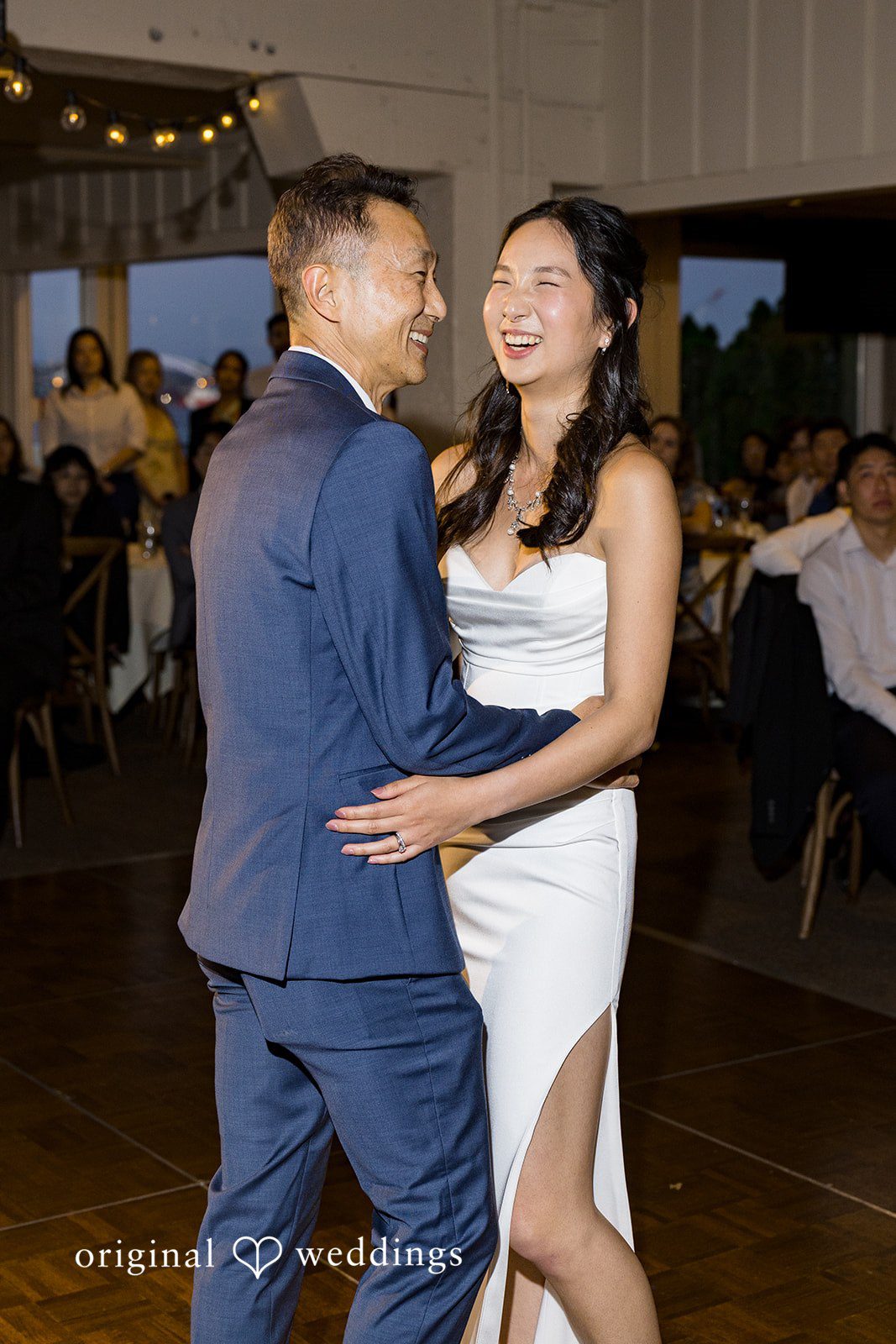 Emily + Paul A bride and groom sharing their first dance together surrounded by wedding guests.