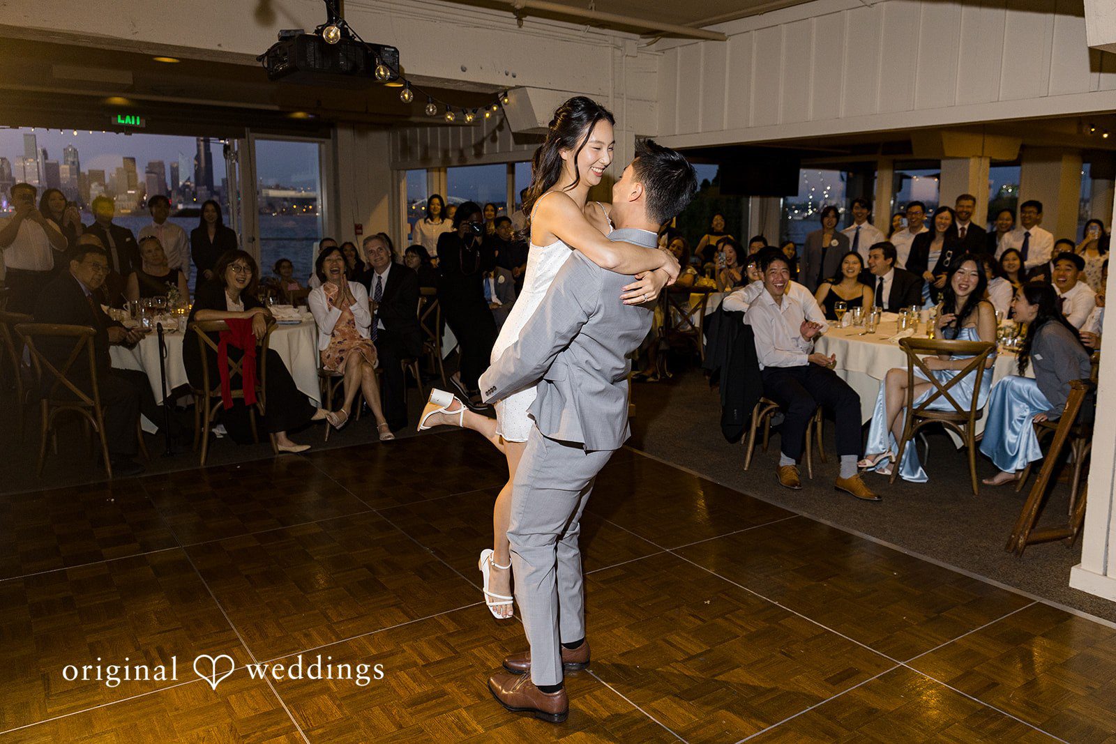 Emily + Paul A bride and groom sharing an energetic dance while guests watch in the background.