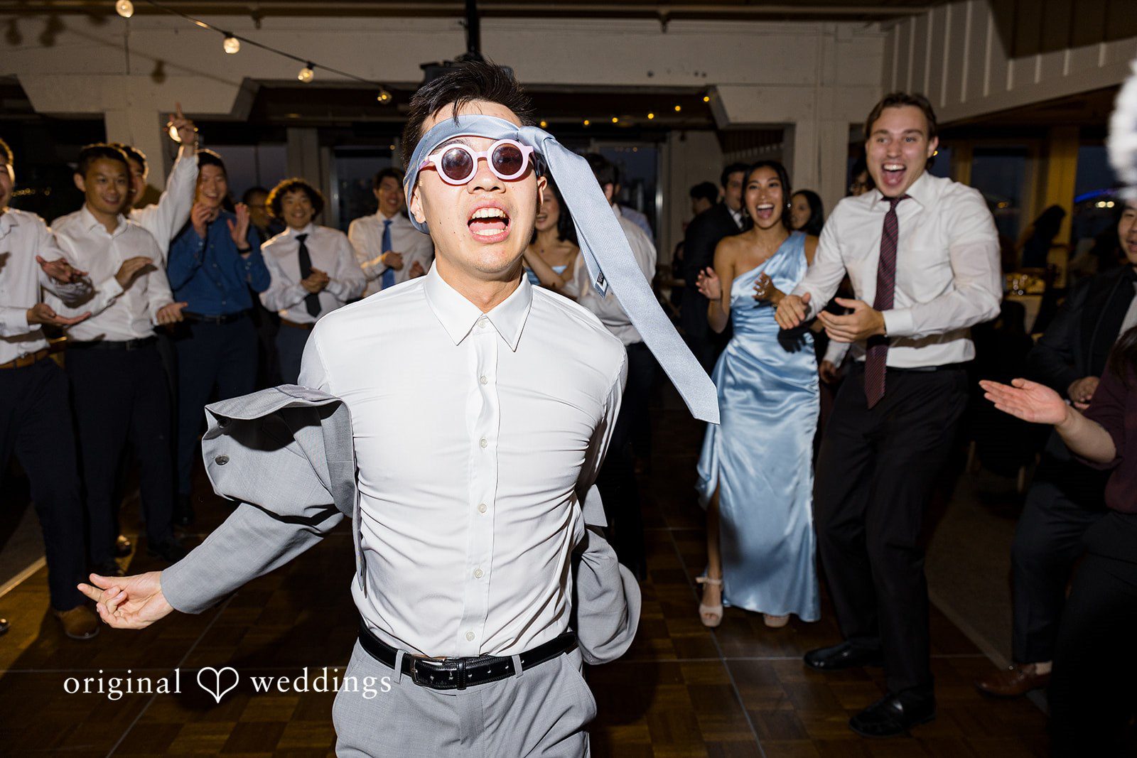 Emily + Paul A groom wearing a veil over his head dancing enthusiastically at the reception.