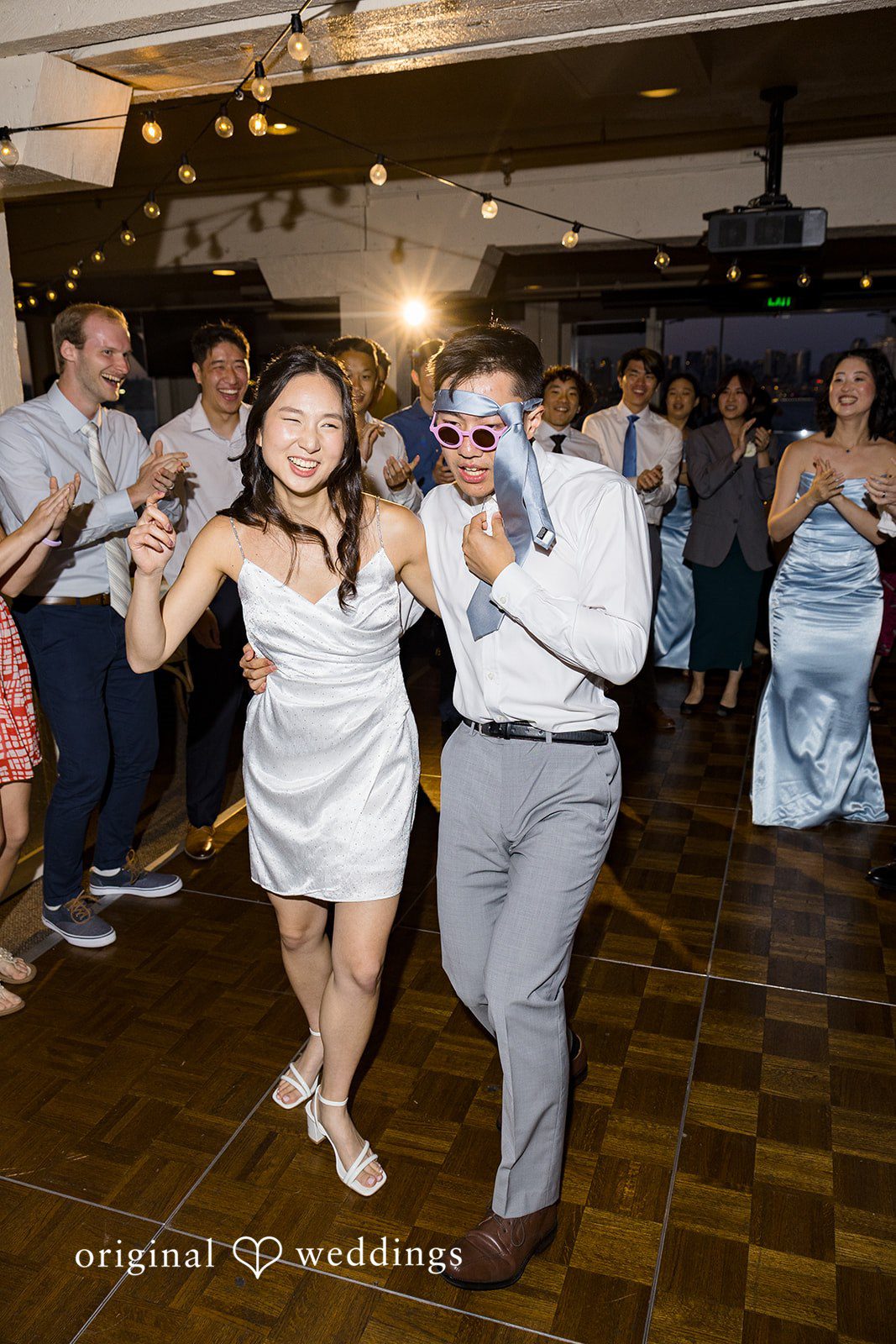Emily + Paul A bride and groom dancing dynamically while surrounded by a lively crowd of guests.