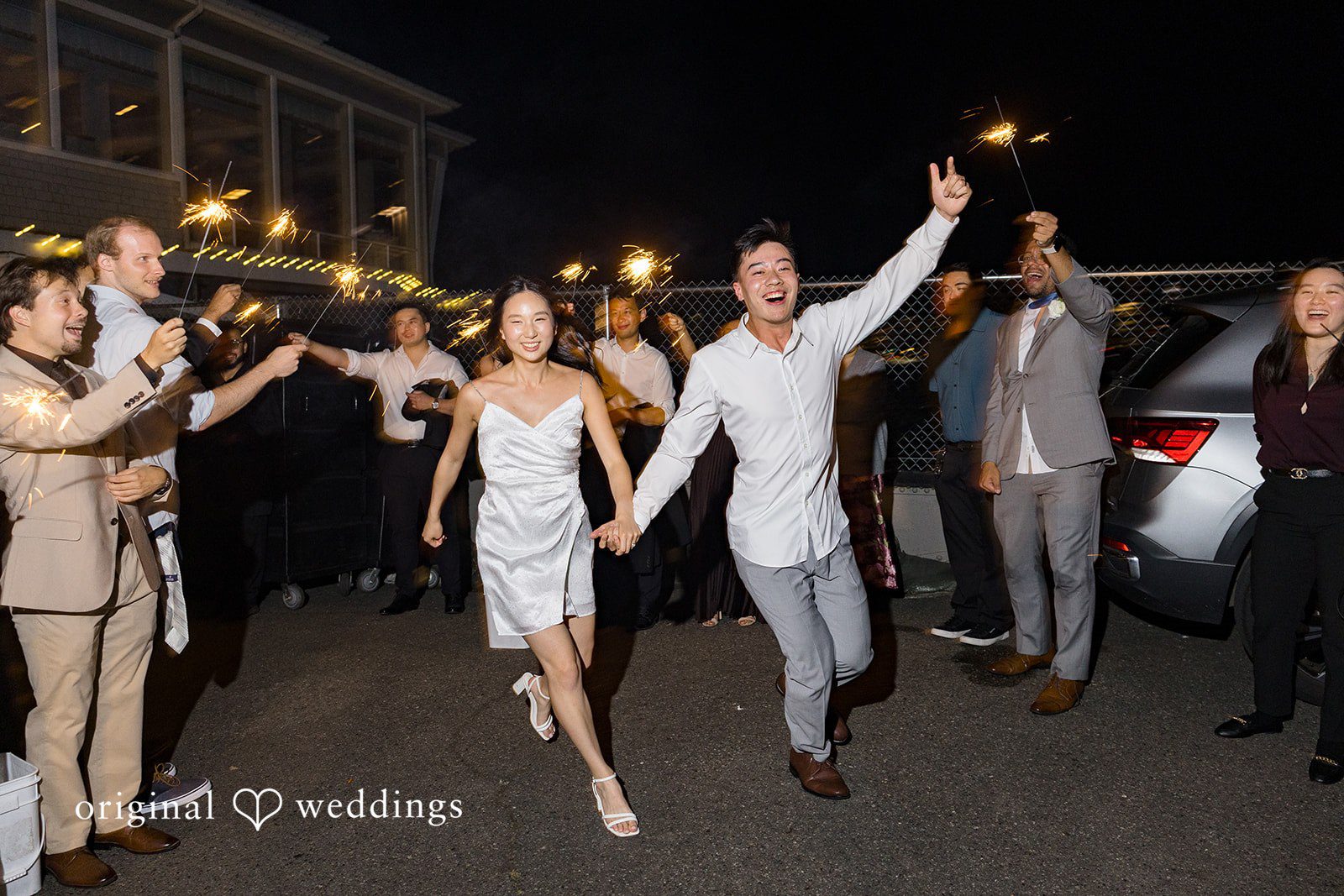 Emily + Paul A bride and groom walking hand-in-hand through a celebratory sparkler grand exit.