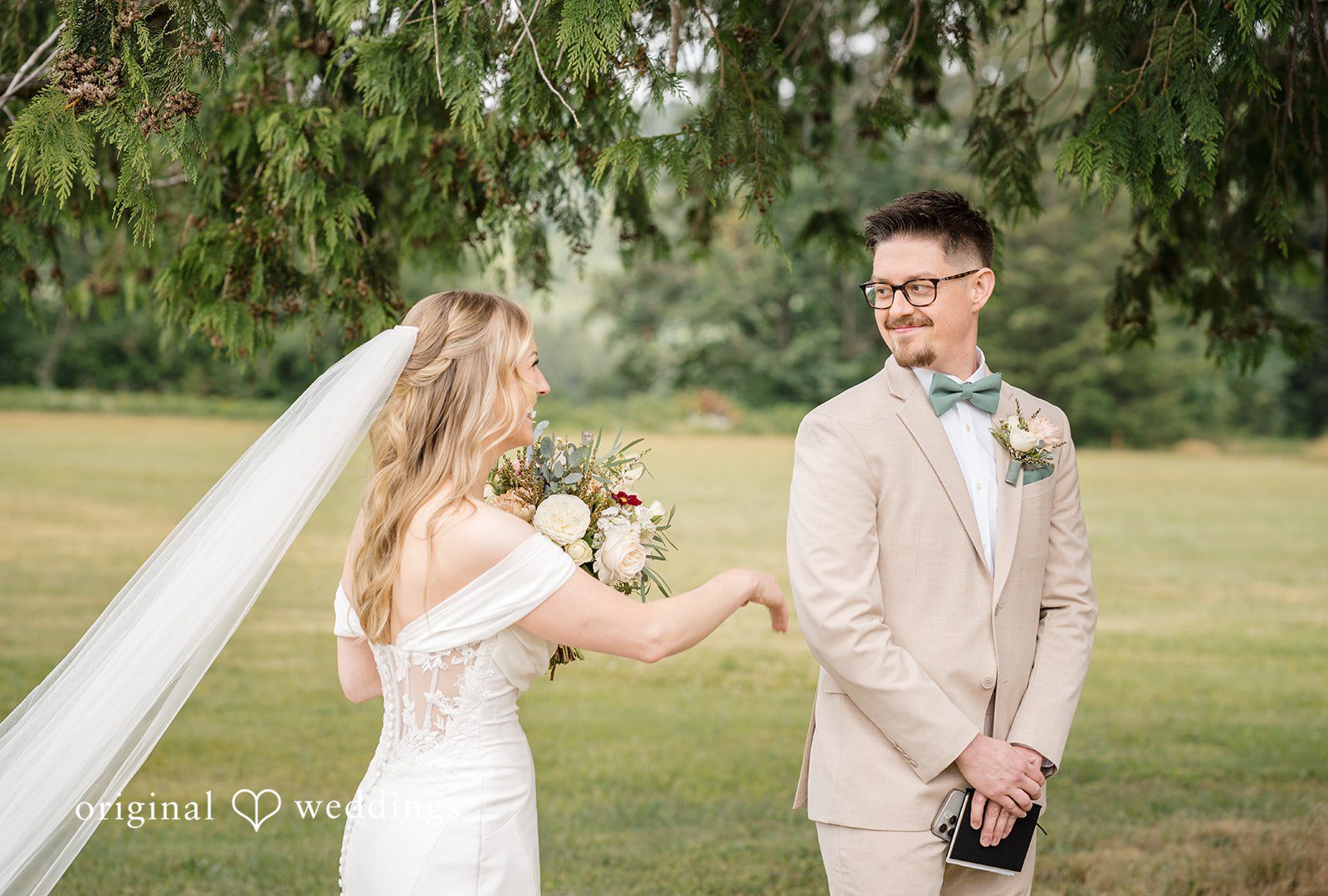 A bride and groom looking at each other in a field.