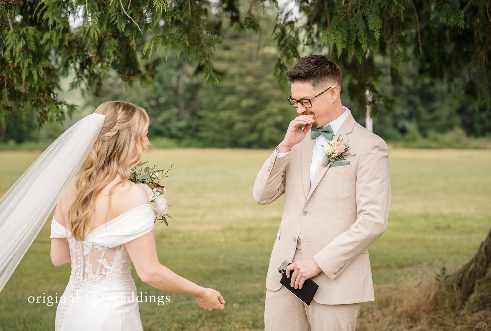 A bride and groom standing close together in a grassy field.