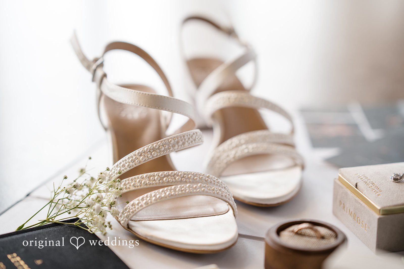 A pair of elegant white bridal high heels placed next to a small dish.
