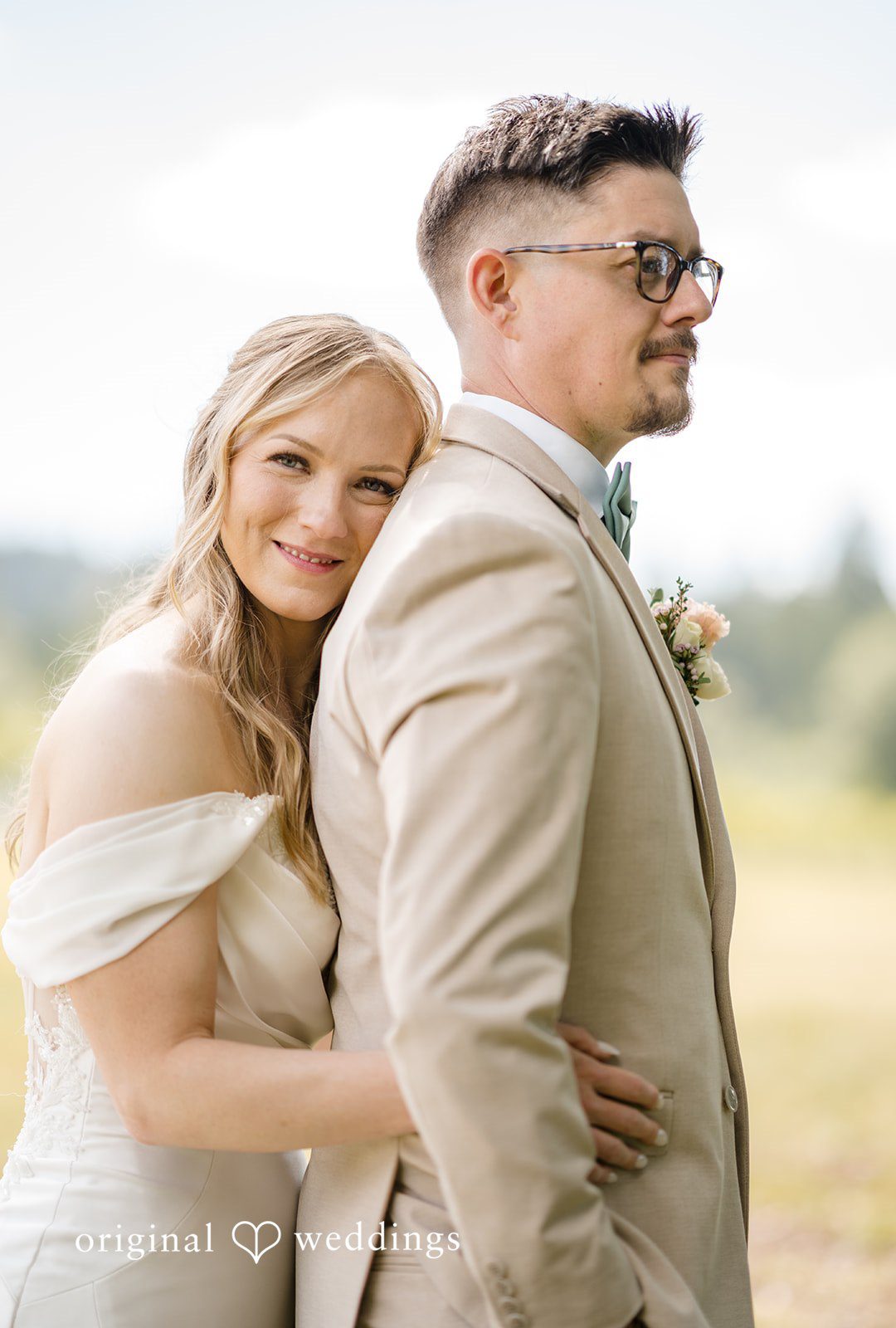 A bride resting on a groom's shoulder as they pose together.