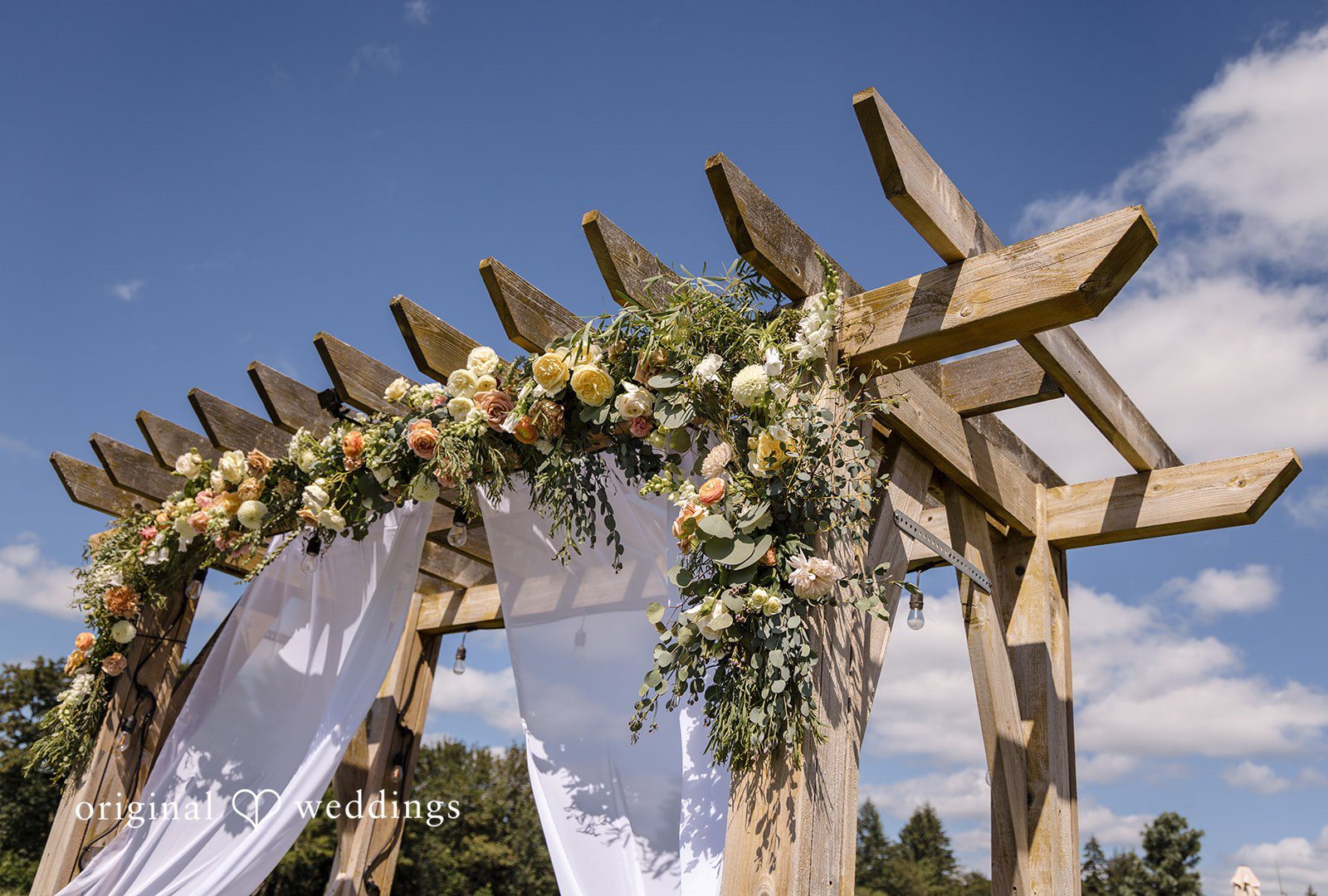 A wooden wedding arch draped in white fabric.