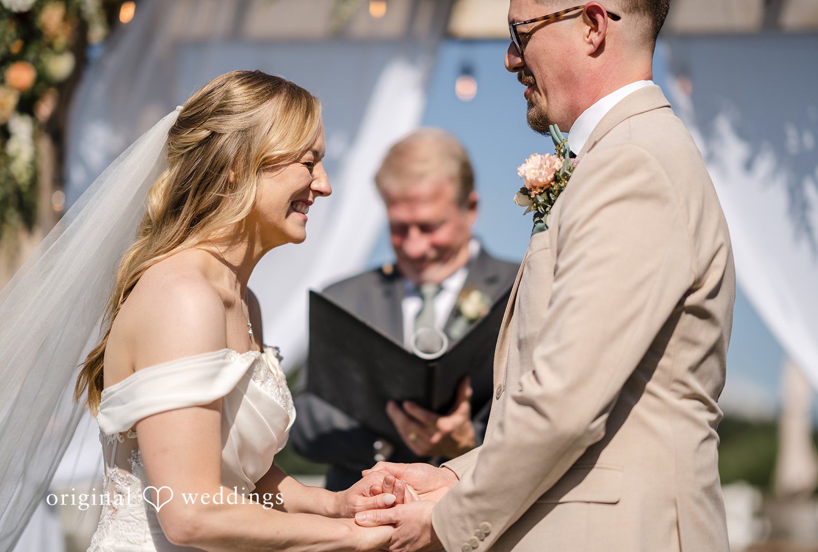 A bride and groom smiling during their wedding vows.