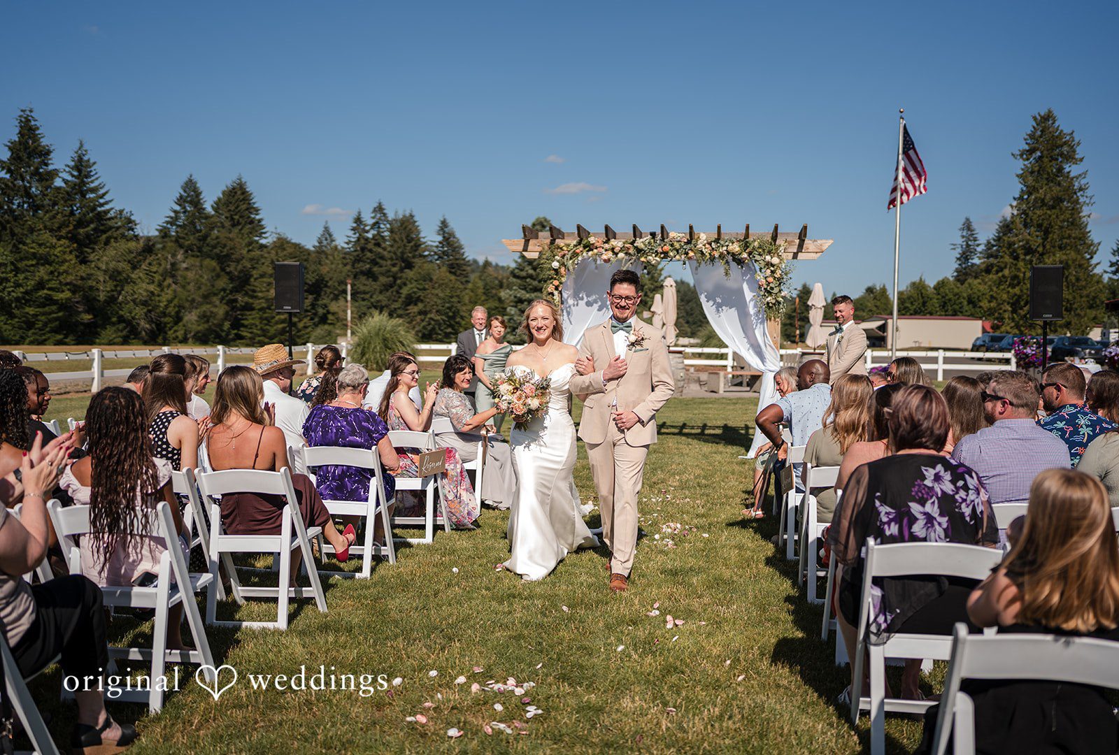A wide view looking down a decorated wedding aisle lined with chairs toward an altar.