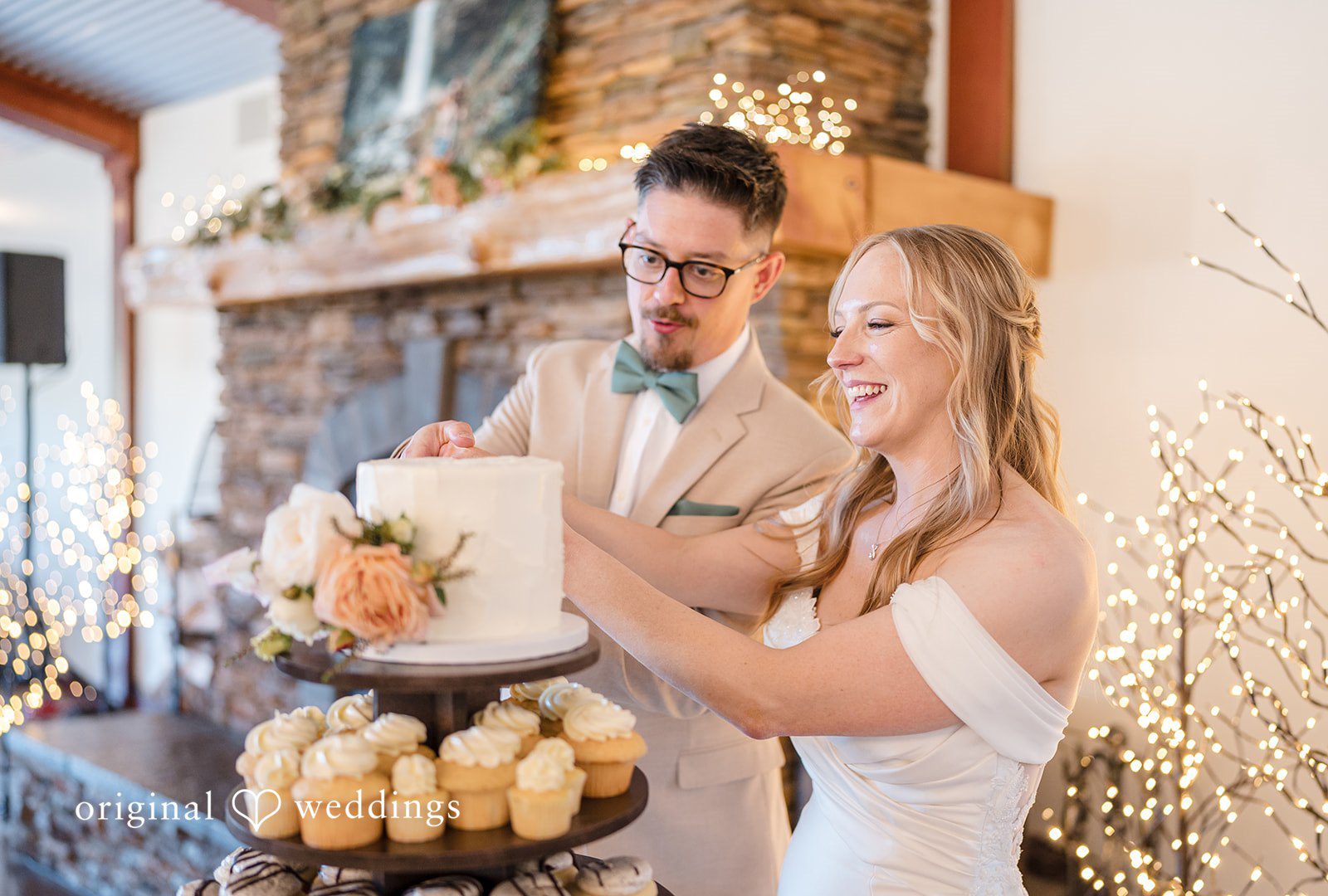 A bride and groom laughing together next to a tiered wedding dessert display.