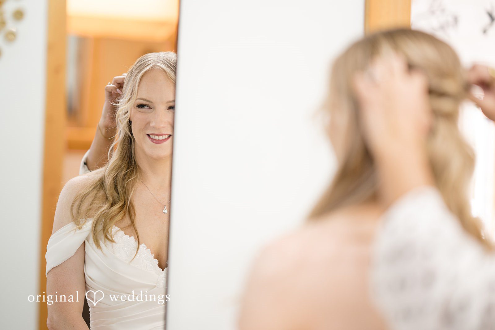 A bride looking at her reflection in a mirror while getting ready.