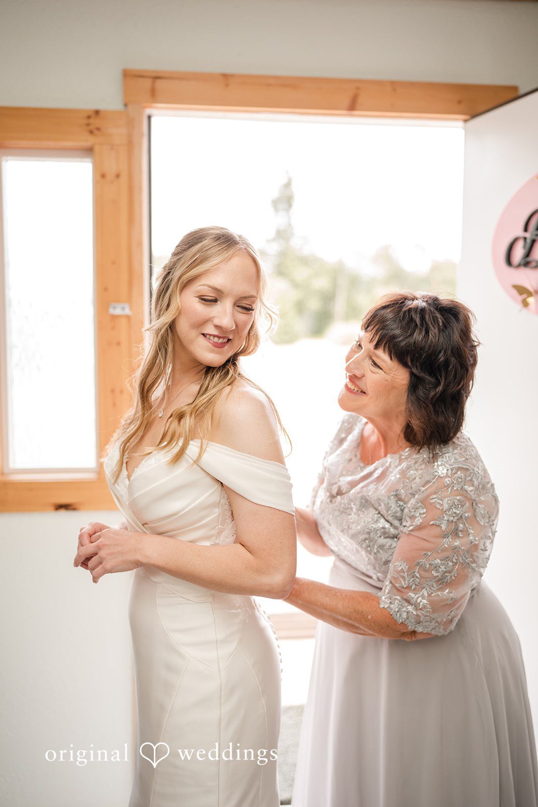 A bride hugging a family member in a well-lit room.
