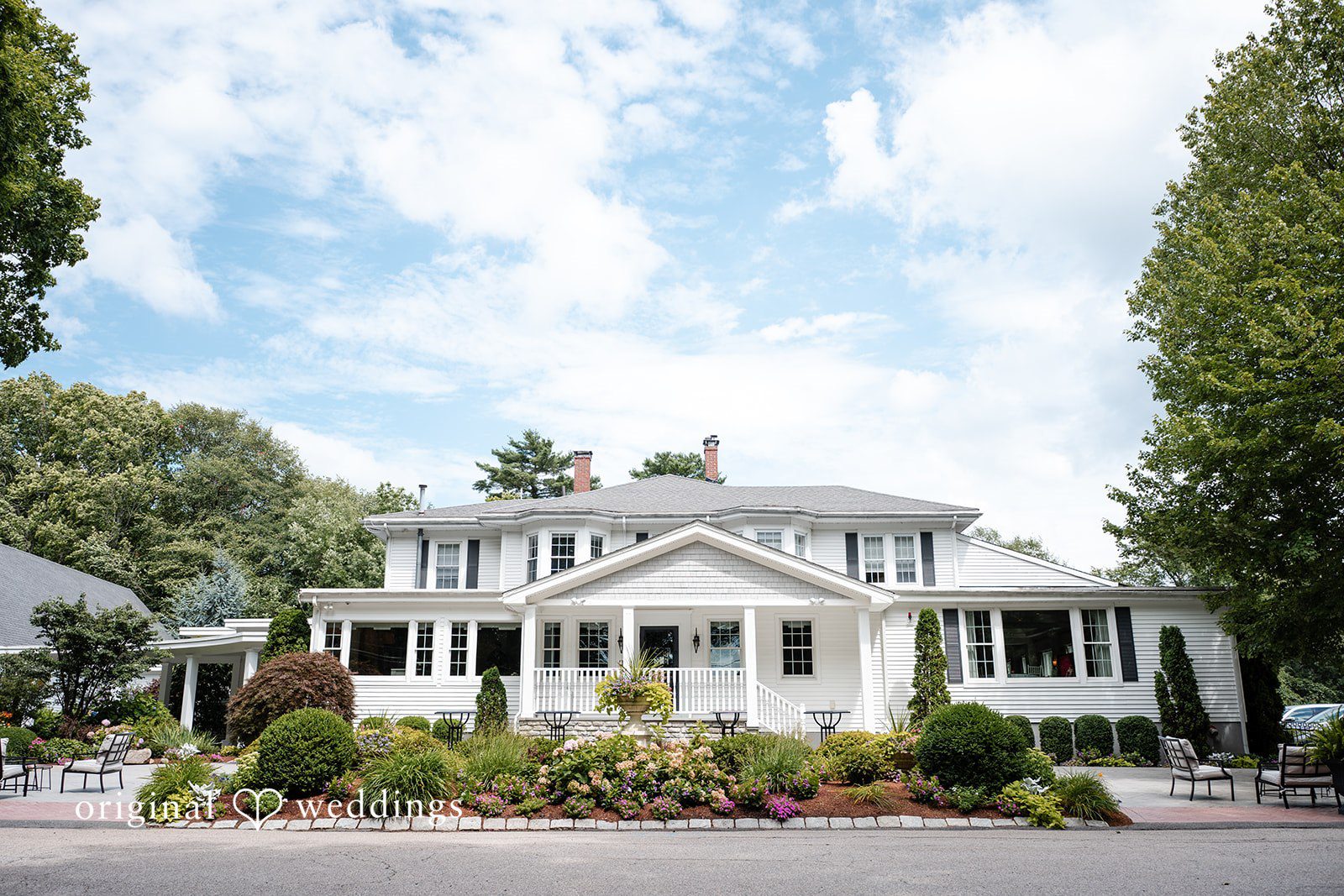 White estate building surrounded by lush green trees.