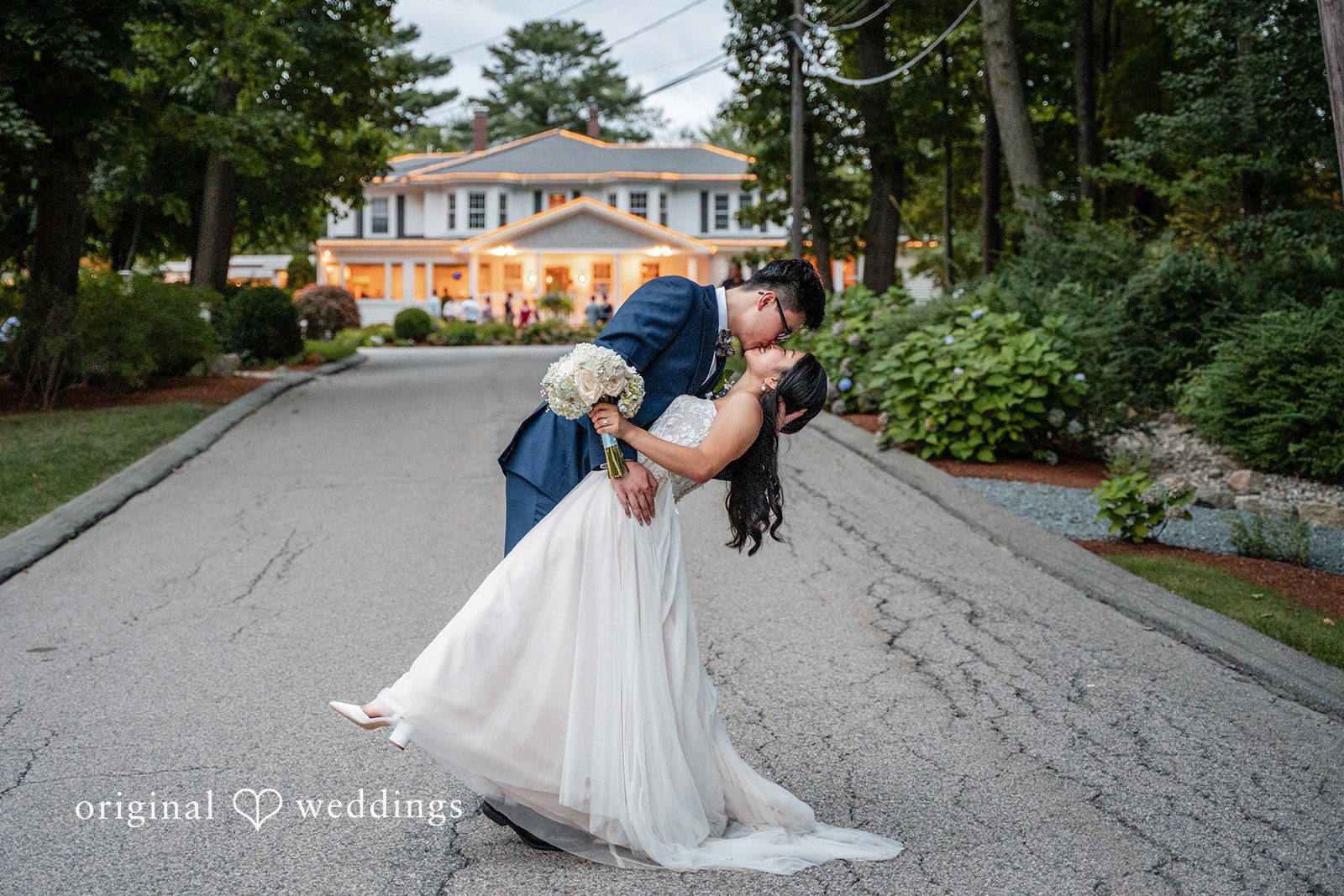 Bride dipping backwards during a dance with the groom on an open pathway.