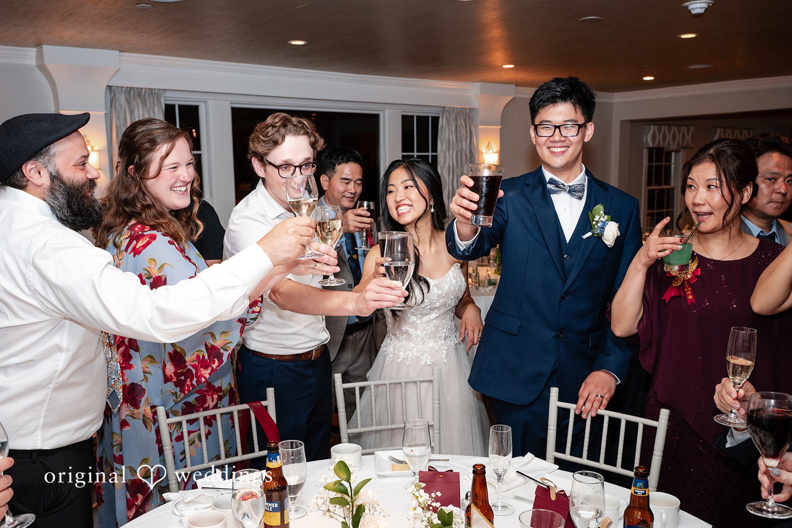 Group of wedding guests smiling and posing together at a reception table.