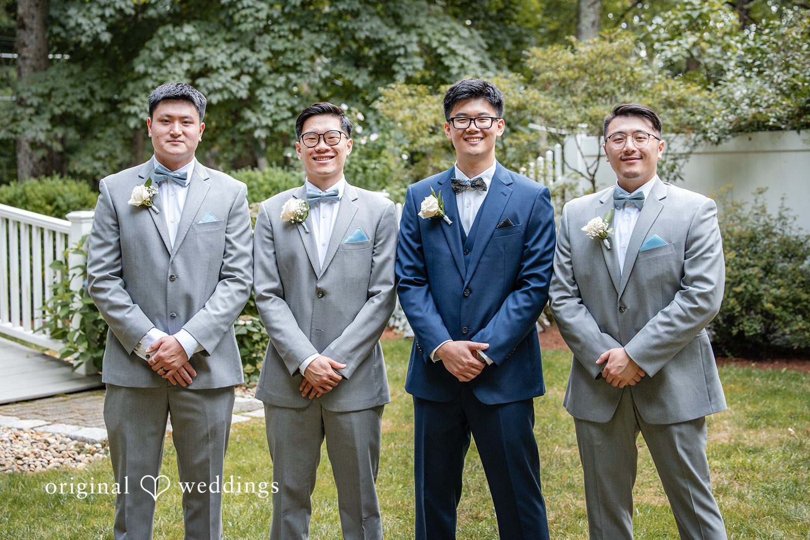 Groom and groomsmen in matching grey and blue suits standing in a row.