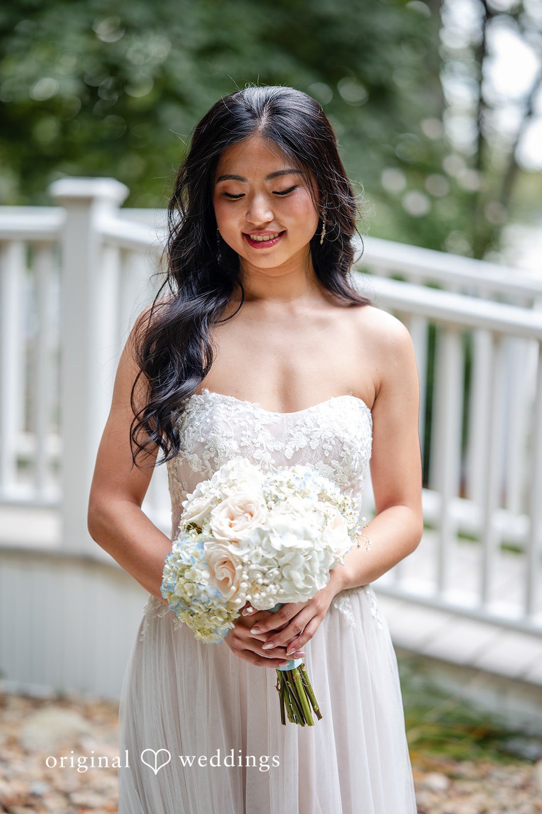 Bride in a strapless gown holding a large bouquet of white flowers.