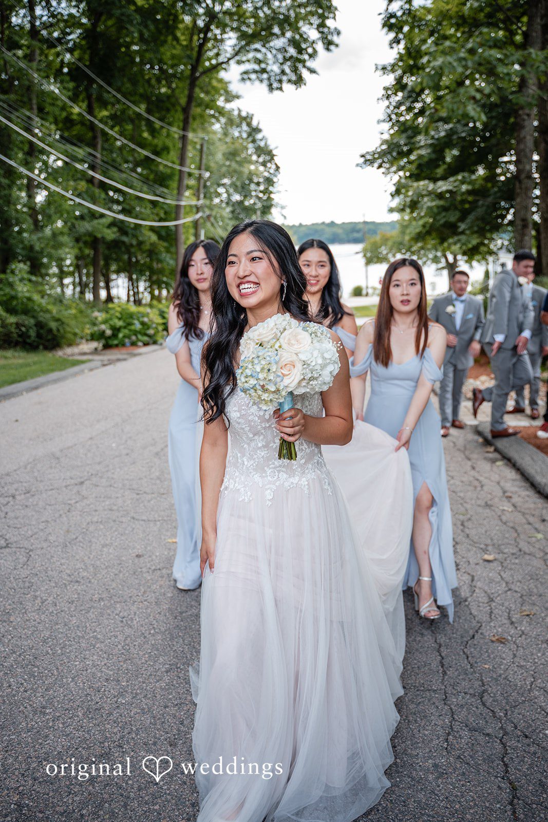 Bride walking along a path with her bridesmaids trailing behind.