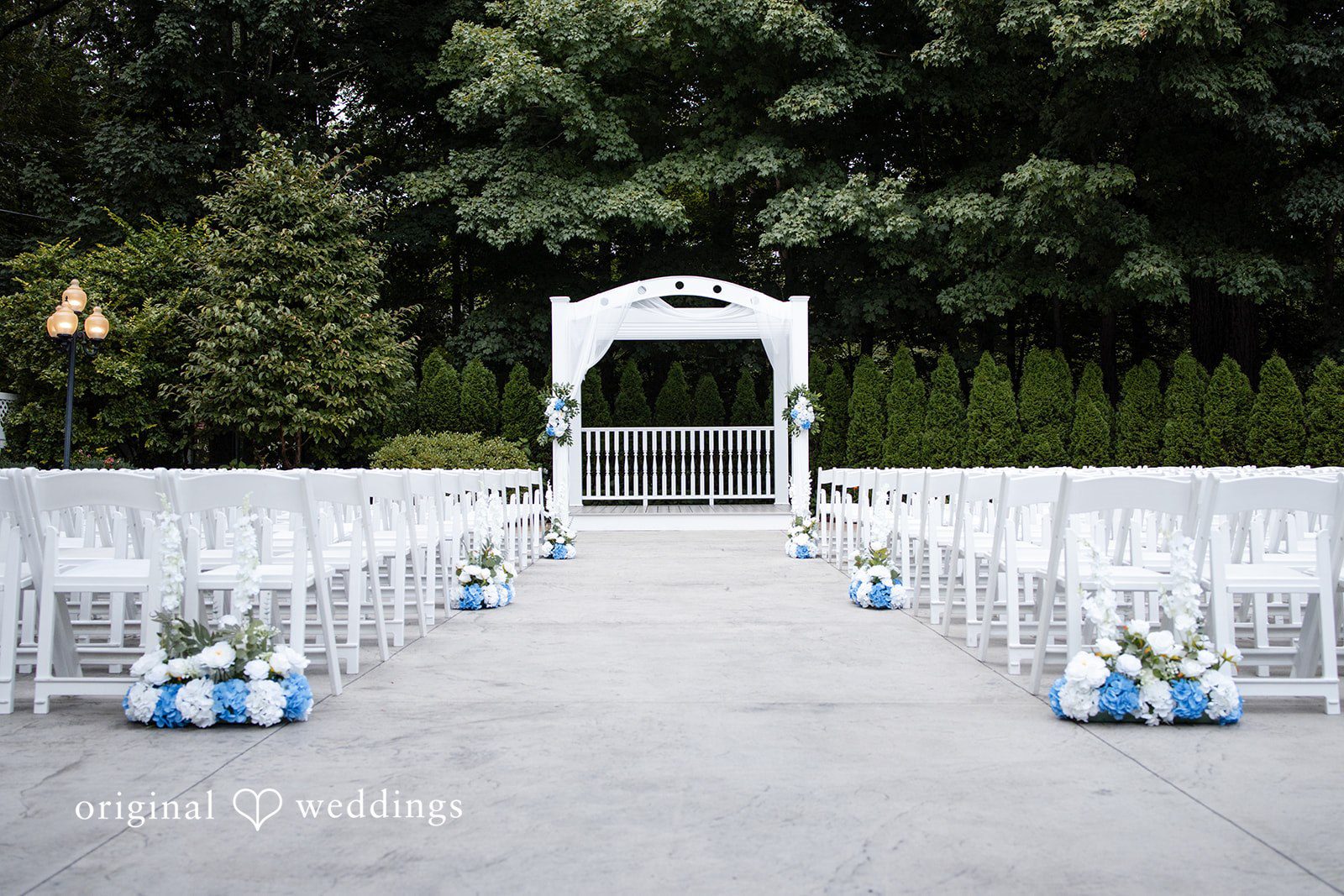 White wedding ceremony arch with rows of seating on a lawn.