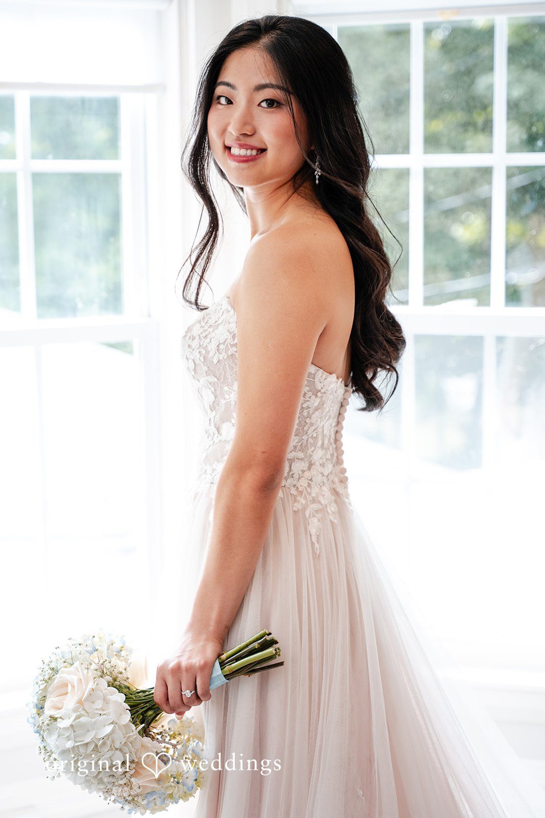 Smiling bride looking over her shoulder while wearing a white dress.