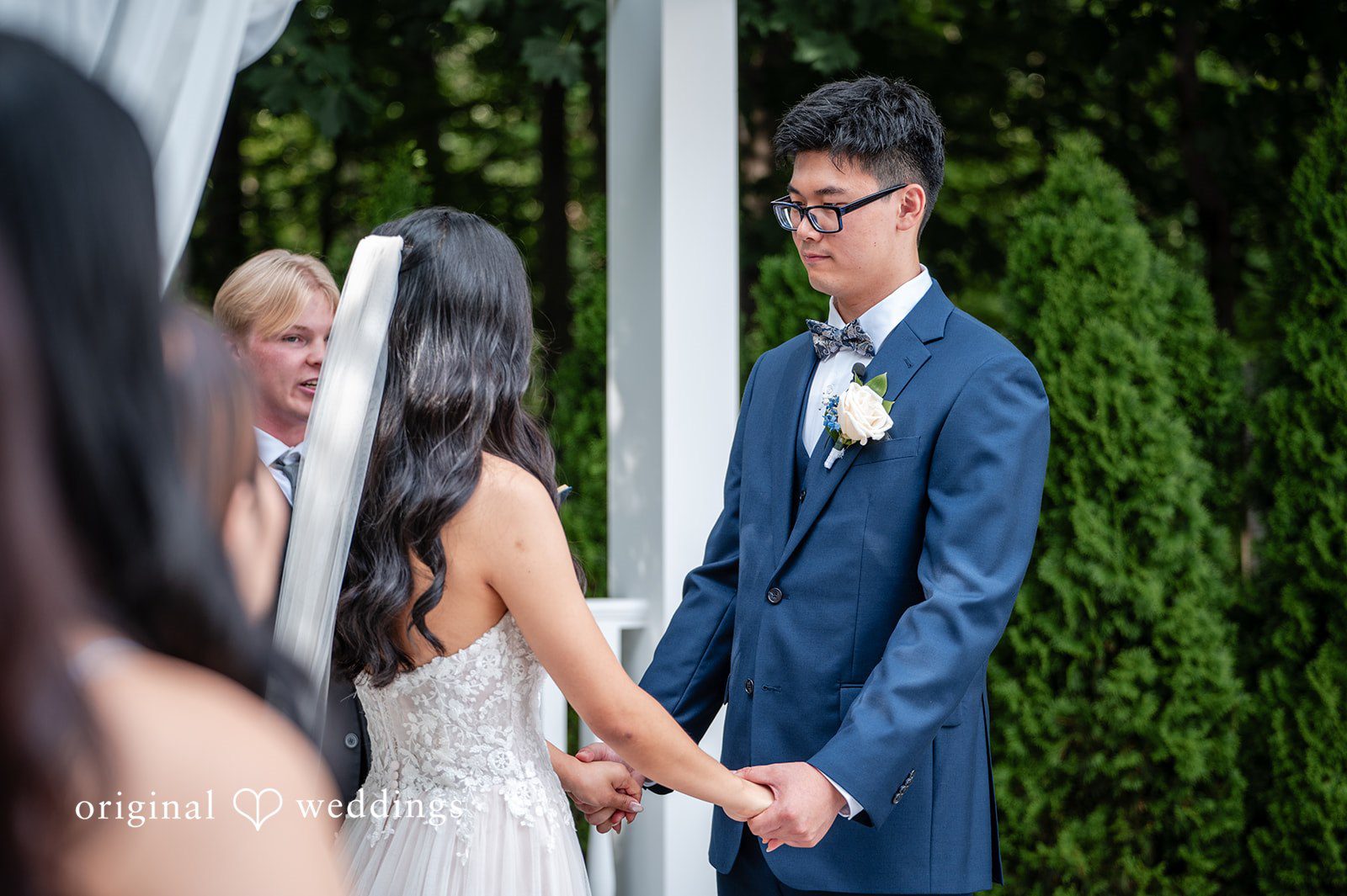 Groom in a blue suit holding hands with a bride in a white gown.
