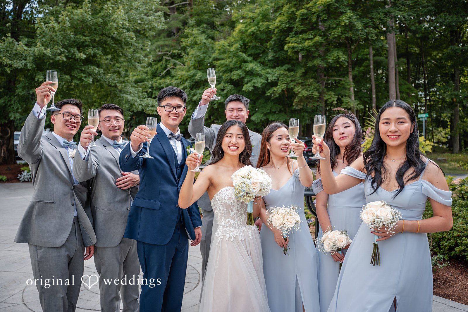 Large wedding party raising their hands in celebration during a group photo.