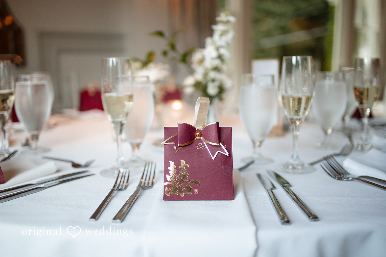 Wedding reception table setting with plates, silverware, and wine glasses.