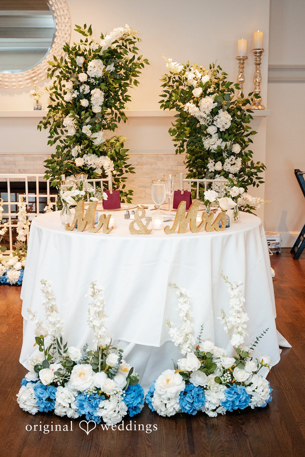 Decorated sweetheart table with white flowers and drapery.
