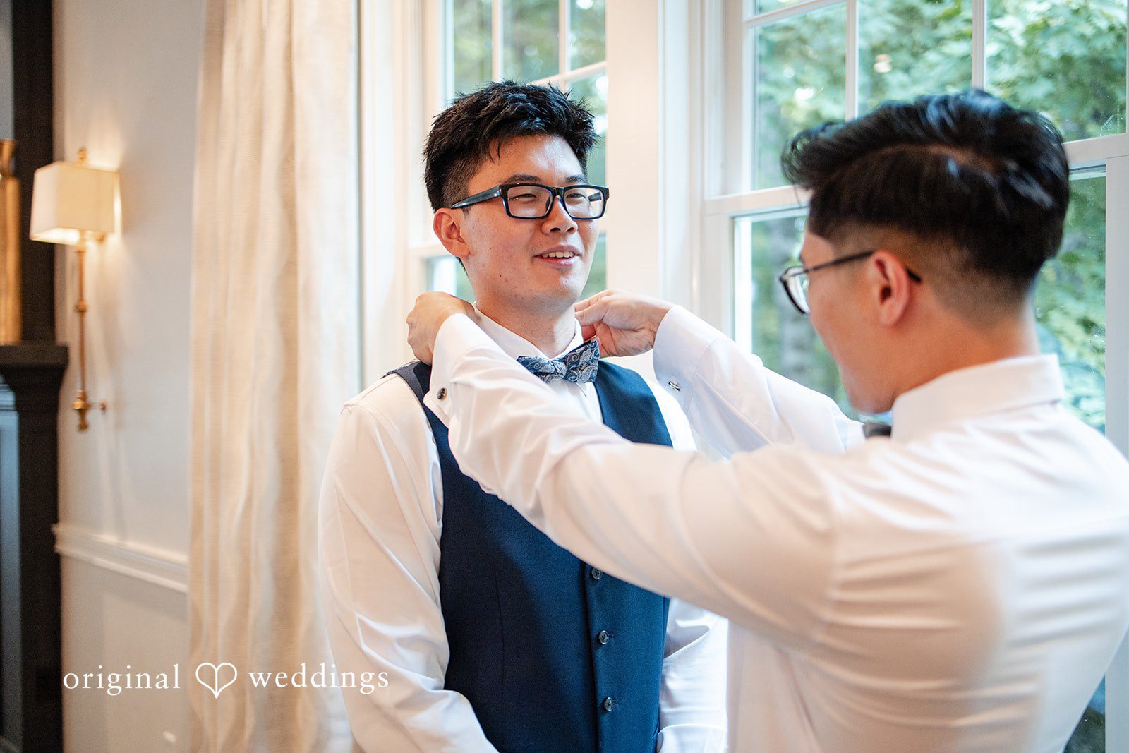Man assisting the groom with his collar and suit details.