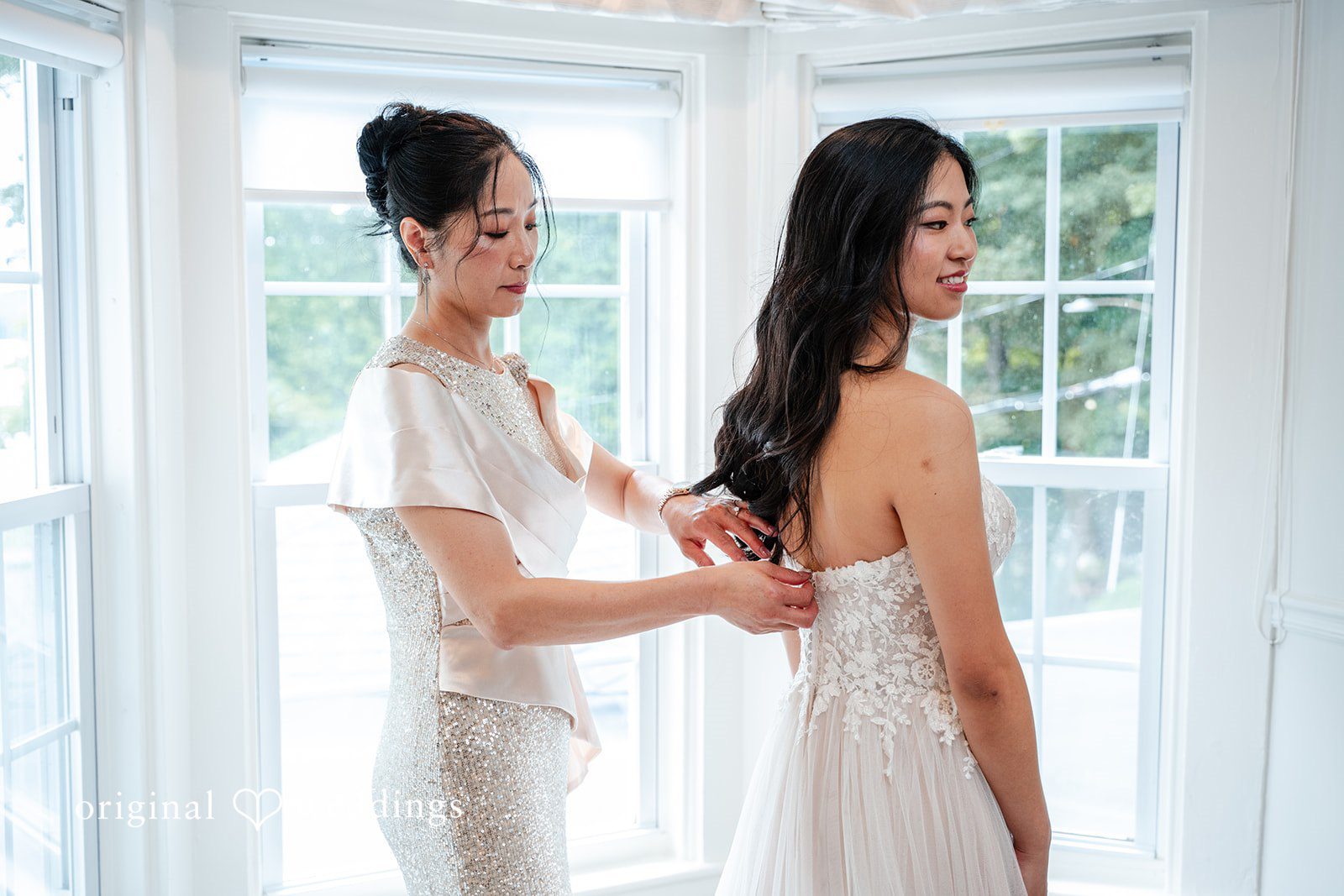 Bridesmaid assisting the bride with the back of her wedding gown.