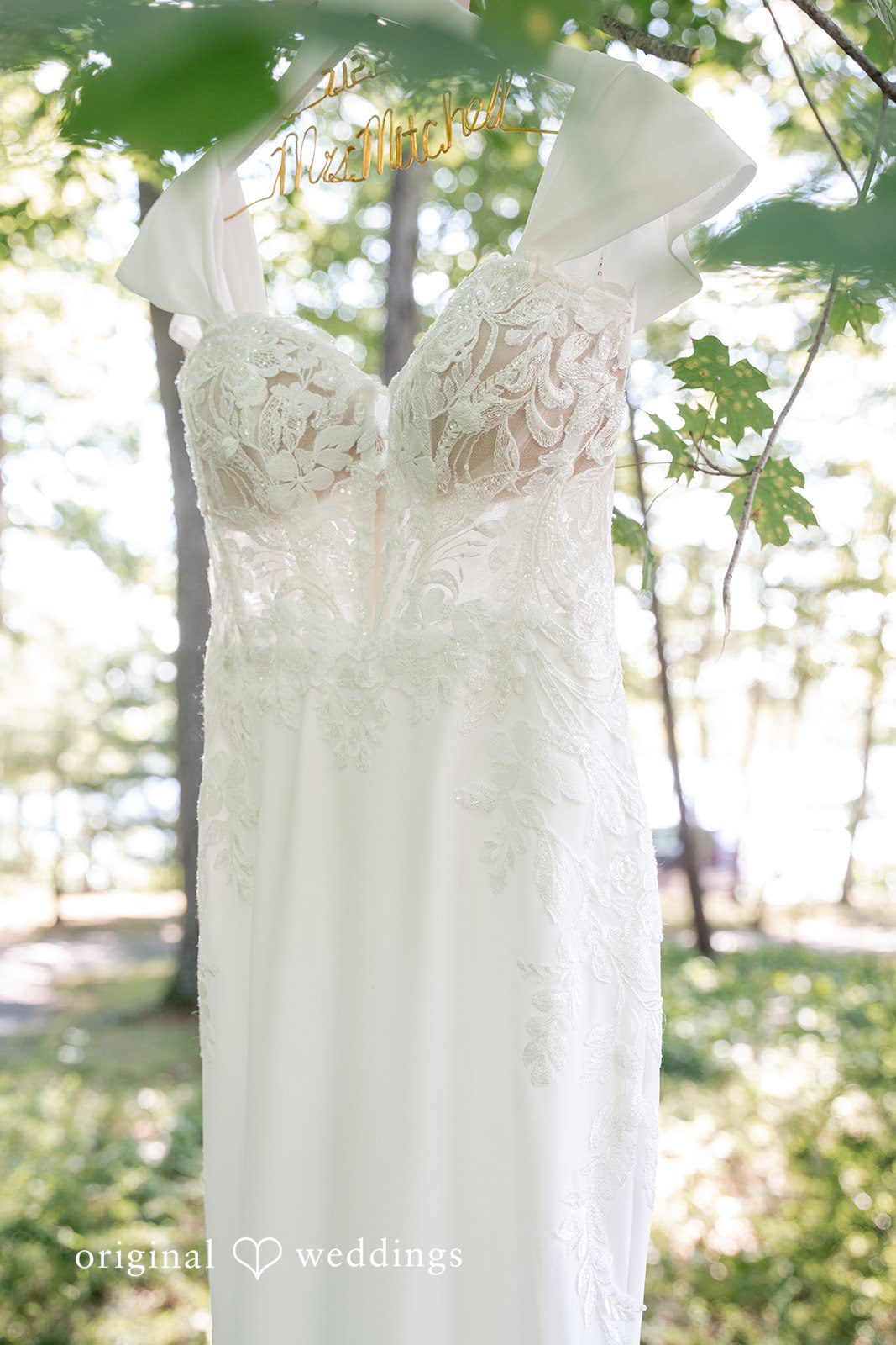 Melissa + Walter A close-up view focusing on the delicate lace detailing of a white wedding dress.