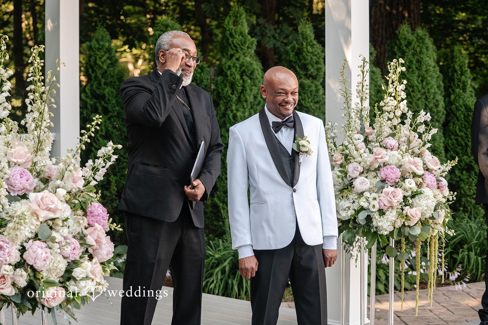 Melissa + Walter A groom standing in a white tuxedo jacket alongside another man in a dark suit.