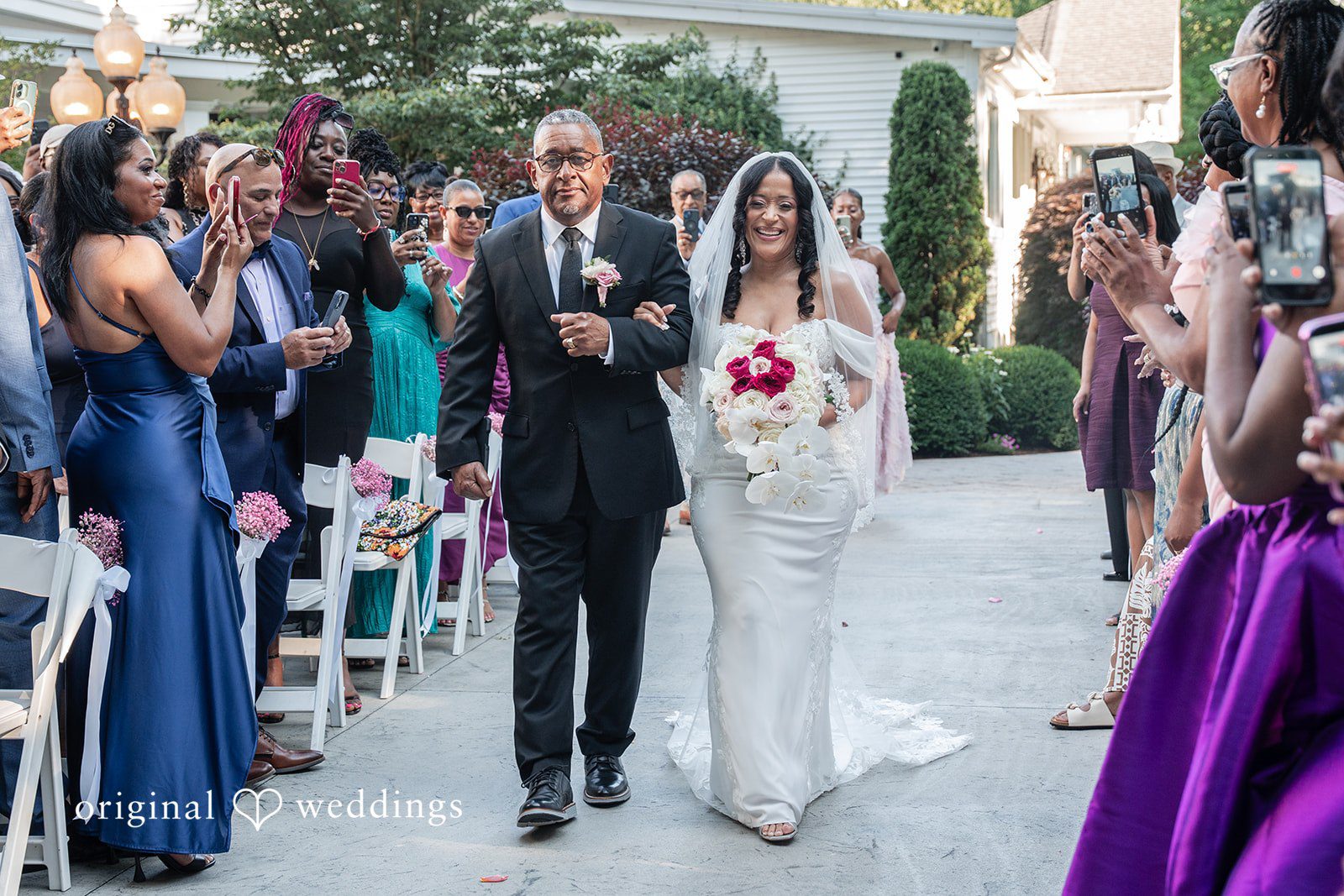 Melissa + Walter A bride walking down the aisle, accompanied by a man on her arm as guests look on.