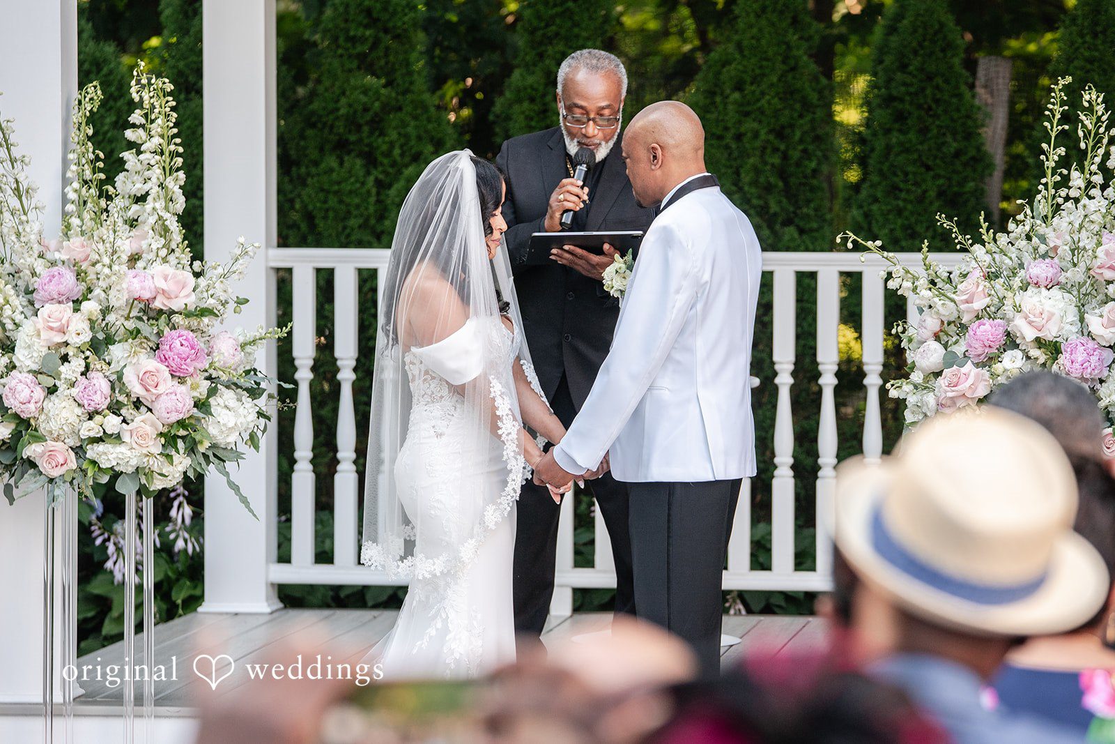 Melissa + Walter A bride and groom standing together during their wedding ceremony under a floral arch.