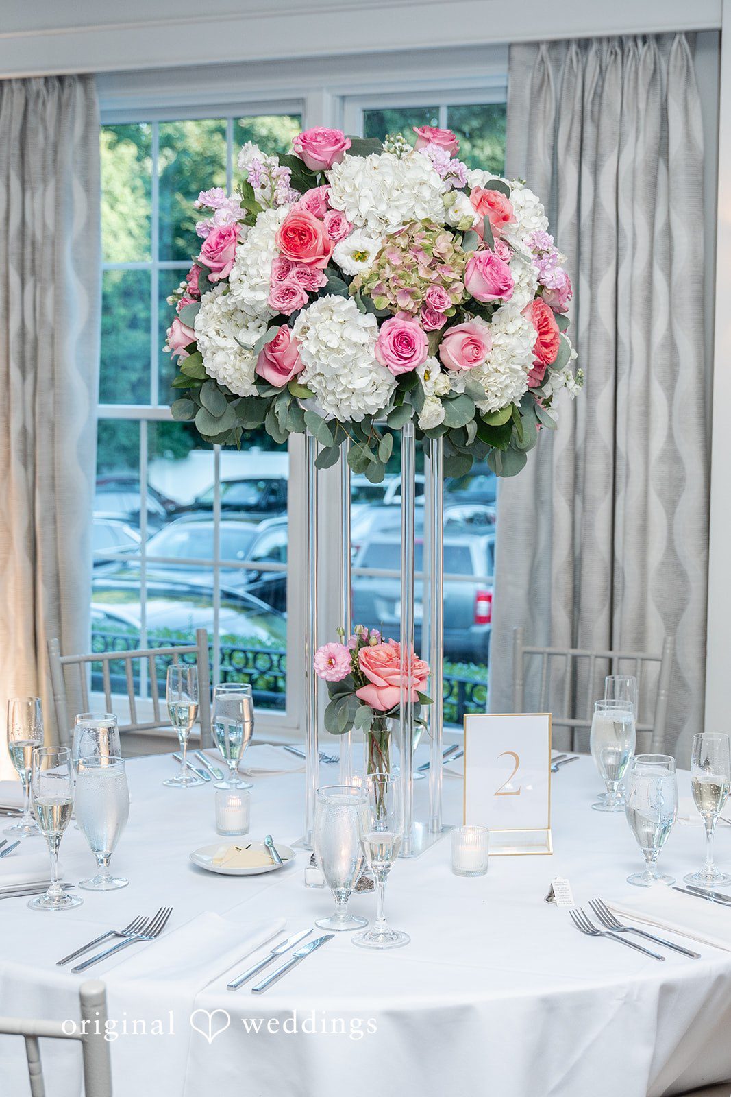 Melissa + Walter A round reception dinner table featuring a tall floral centerpiece with pink and white roses.