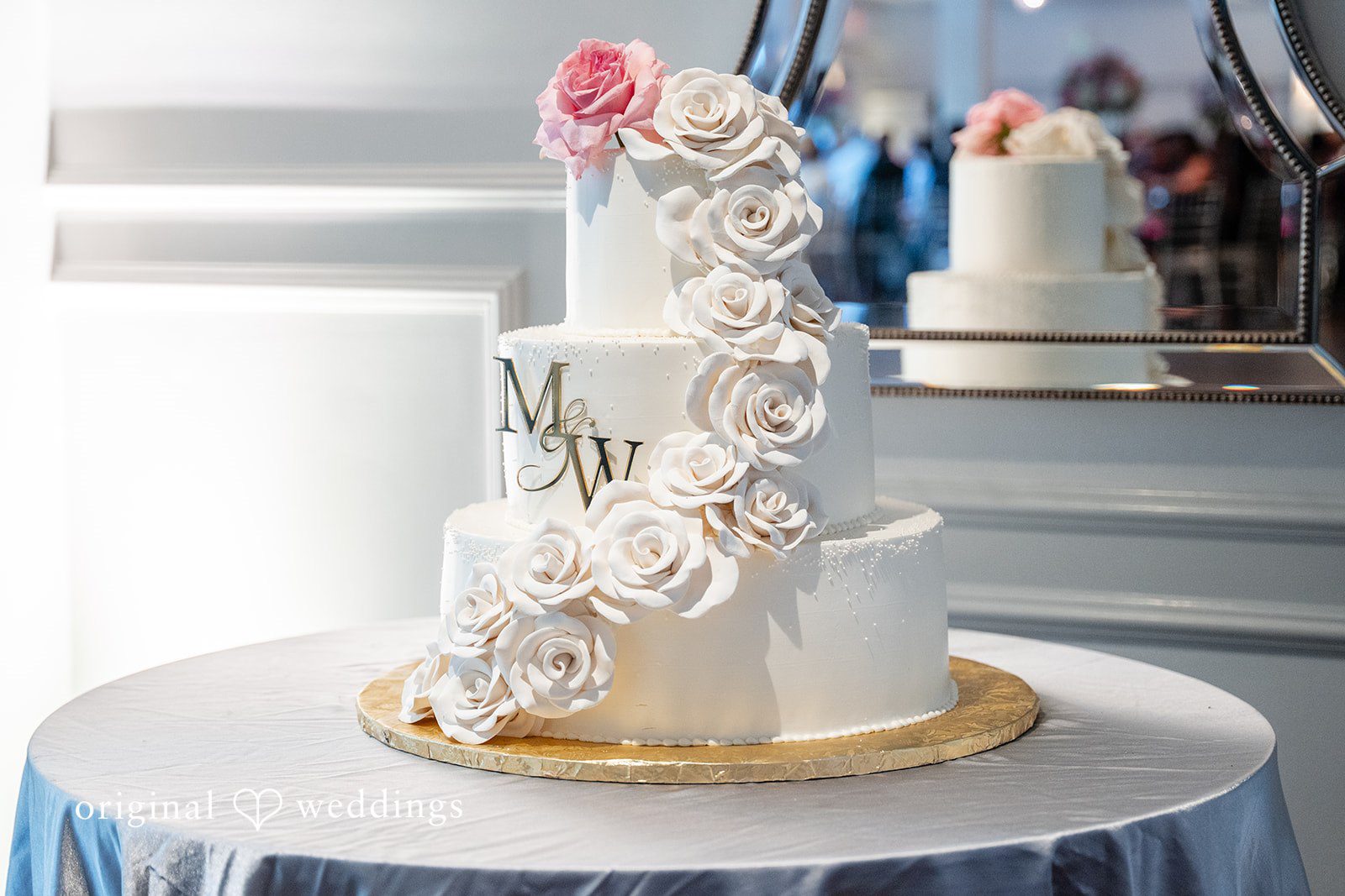 Melissa + Walter A multi-tiered white wedding cake decorated with delicate floral details on a serving table.