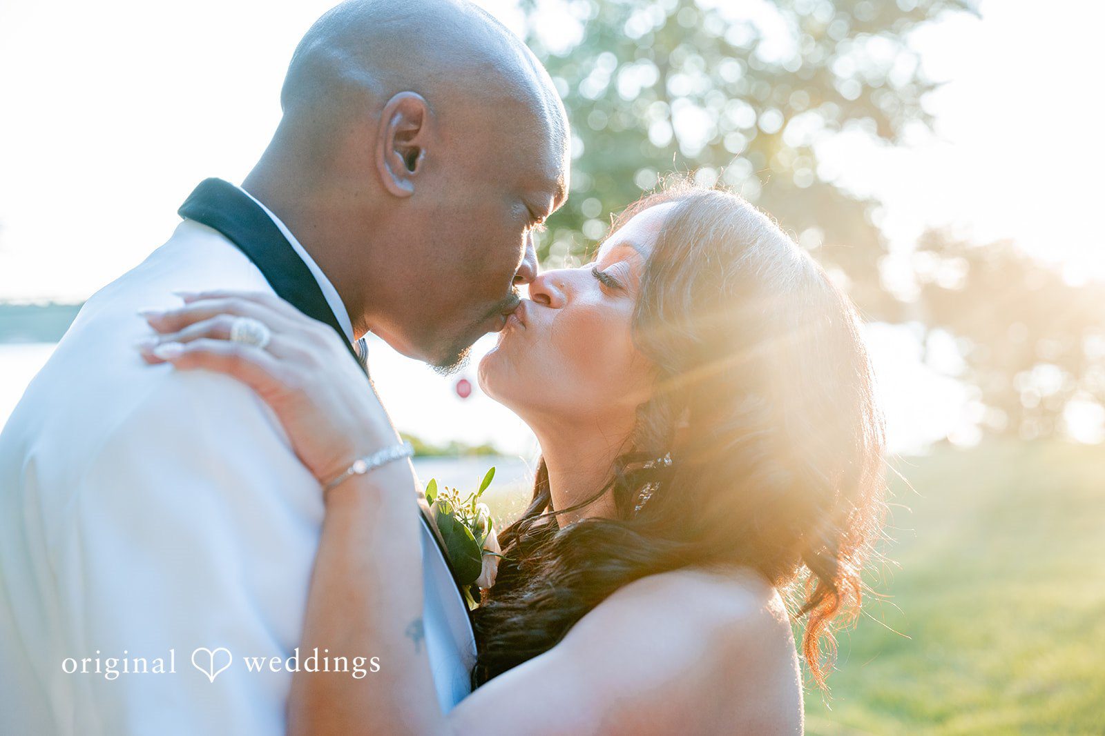 Melissa + Walter A close-up shot of a bride and groom sharing a kiss, softly illuminated by warm light.