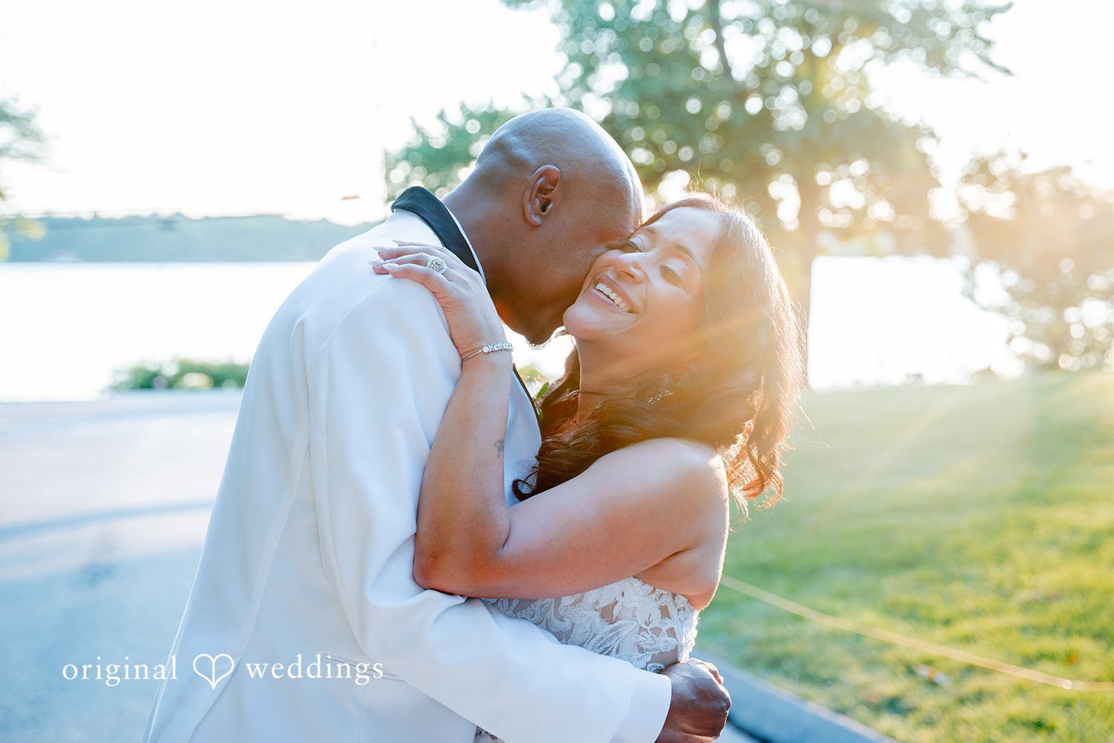 Melissa + Walter A bride and groom embracing and kissing while surrounded by soft, bright lighting.