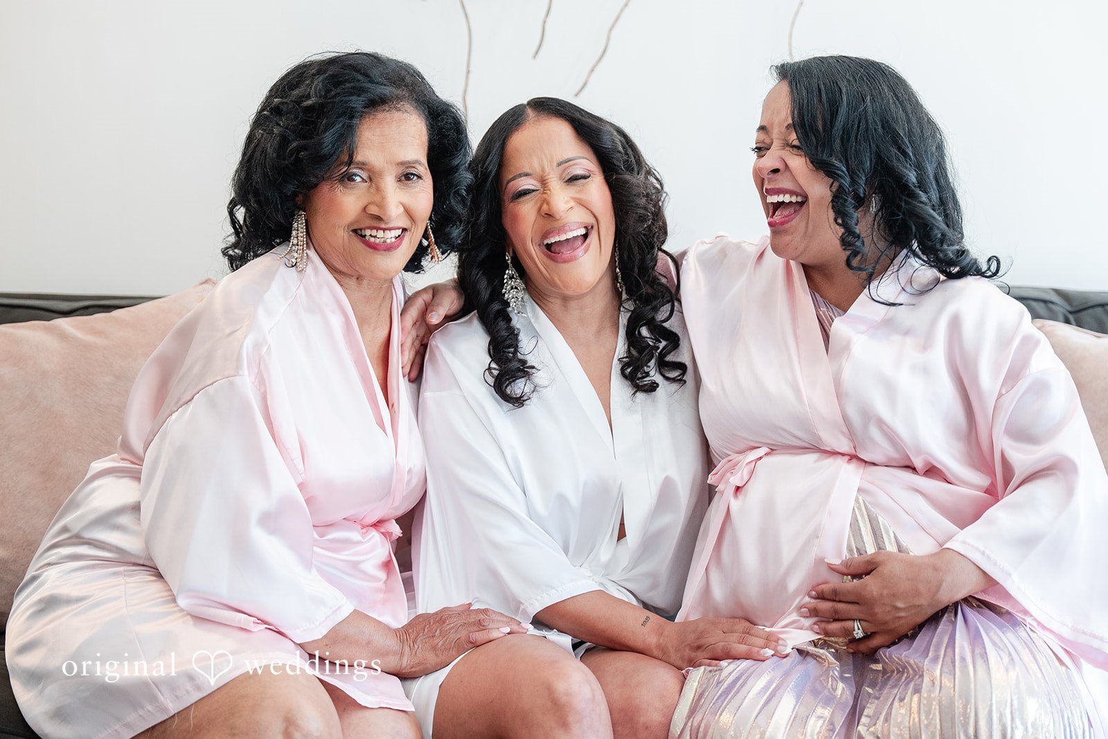 Melissa + Walter A bride and her bridesmaids smiling while wearing matching light pink satin robes.