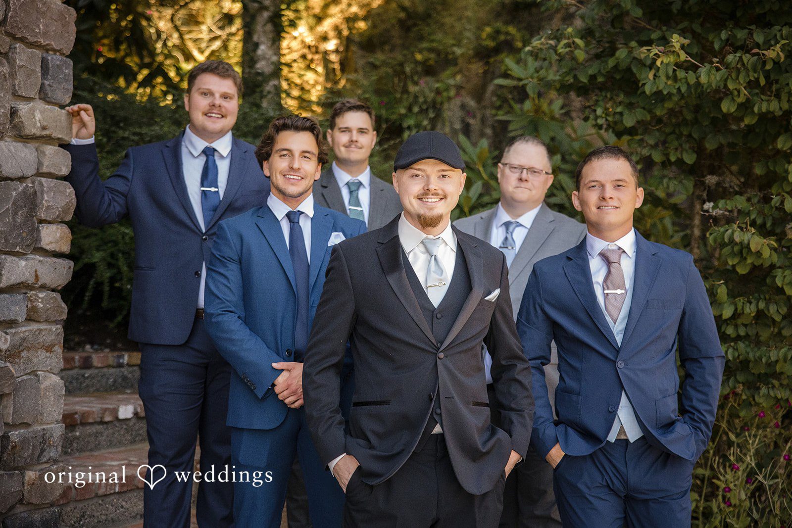 Jade + Nicholas Groom and groomsmen wearing matching blue suits standing close together.