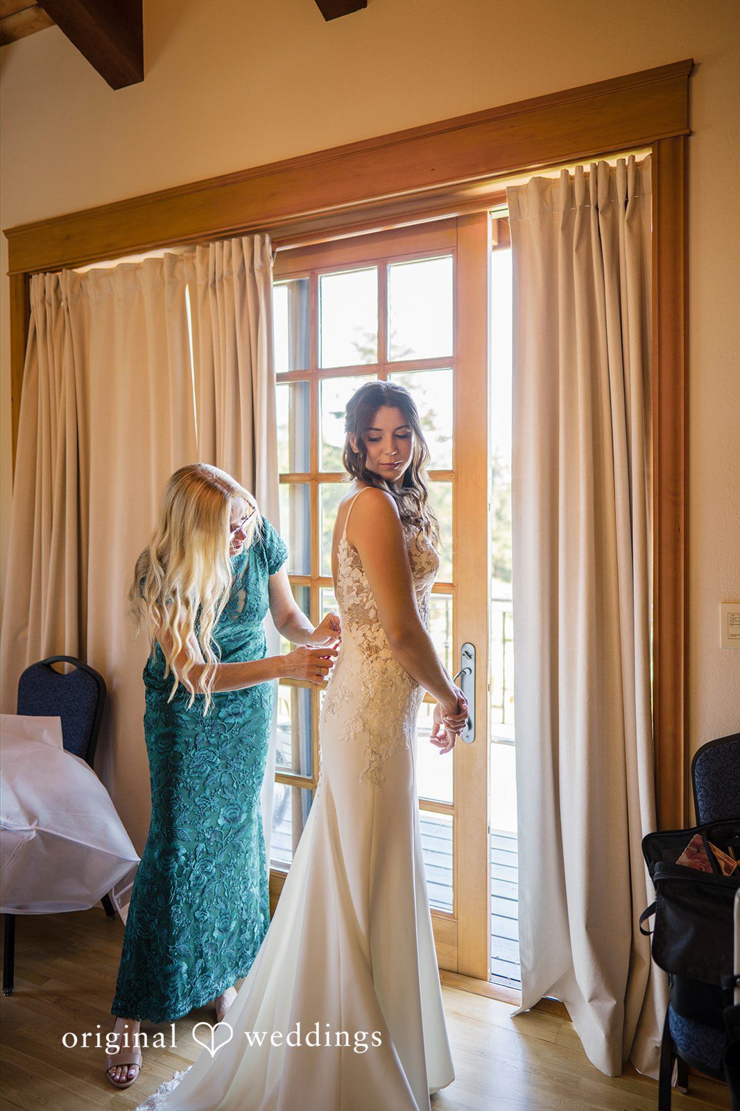 Jade + Nicholas A bride standing inside a room with long white curtains looking toward the window.